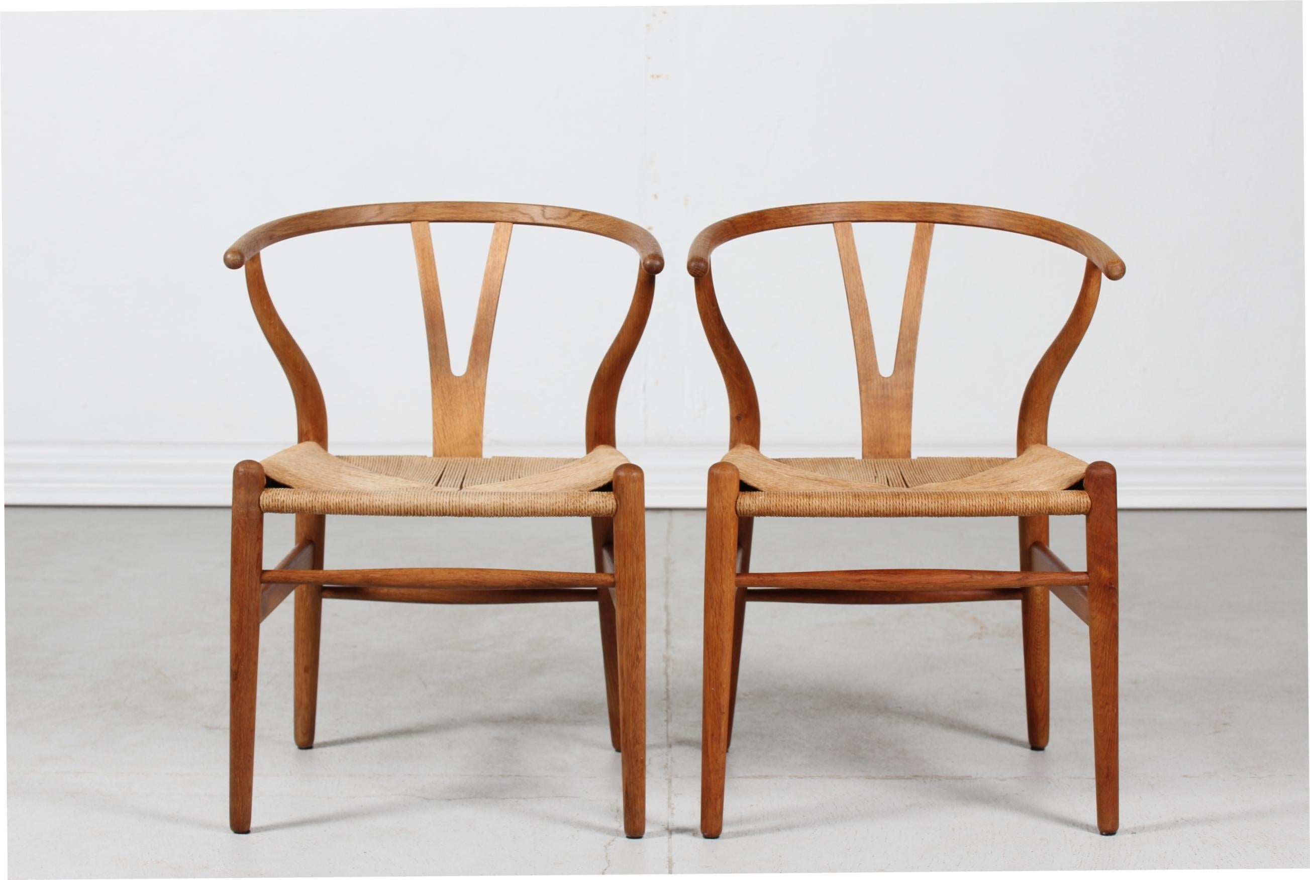 A pair of early Hans J. Wegner (1914-2007) wishbone chairs with burn mark. 
Model no. CH 24 manufactured by Carl Hansen & Son, Denmark.
The wishbone chairs has been in production since 1950.

These chairs purchased by previous owner's parents in