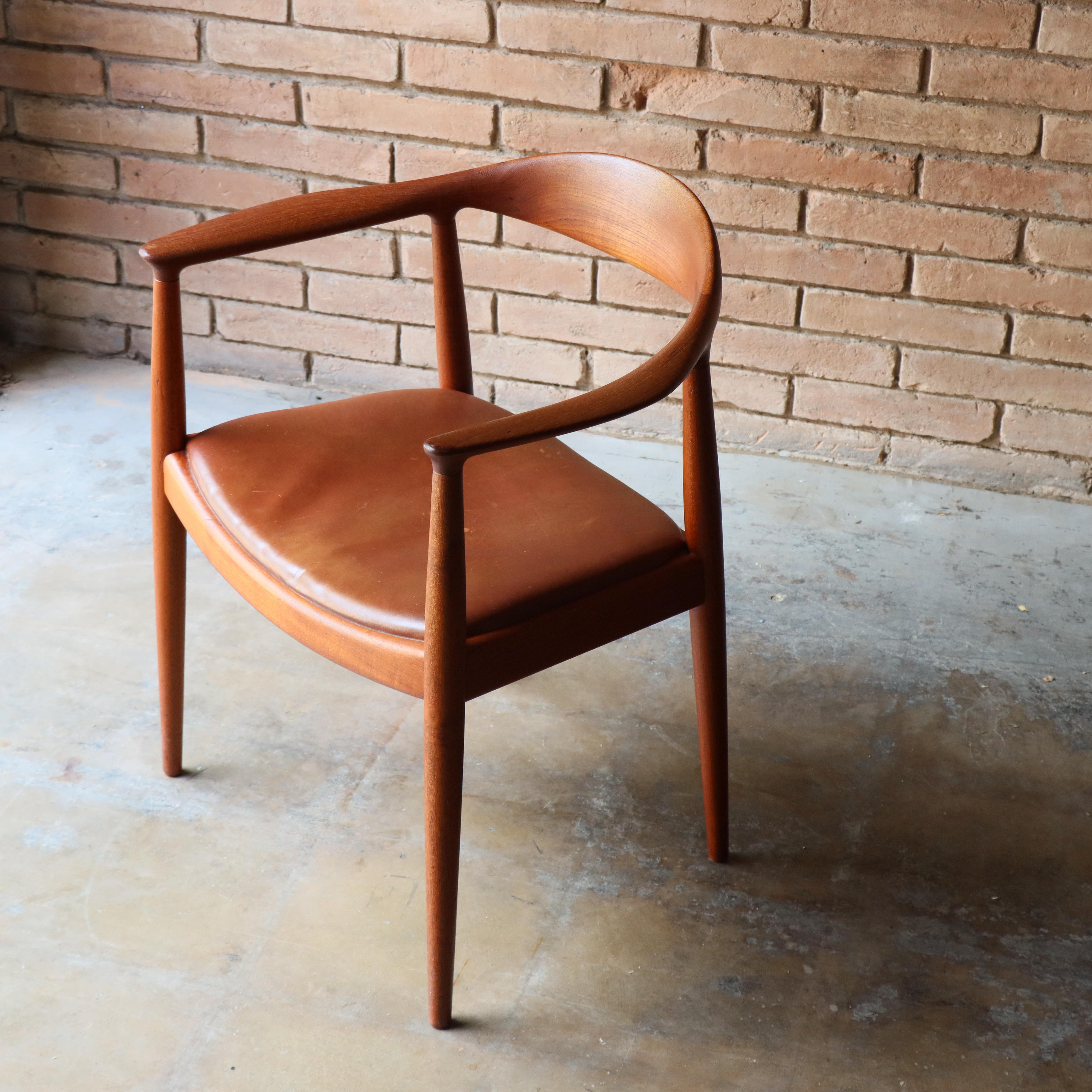 An early “round” chair or “Kennedy” chair designed by Hans Wegner for Johannes Hansen. This example is executed in teak and retains its vintage cognac leather. Model JH 503. Example is fully marked with early Johannes Hansen branding. 

“A chair,”