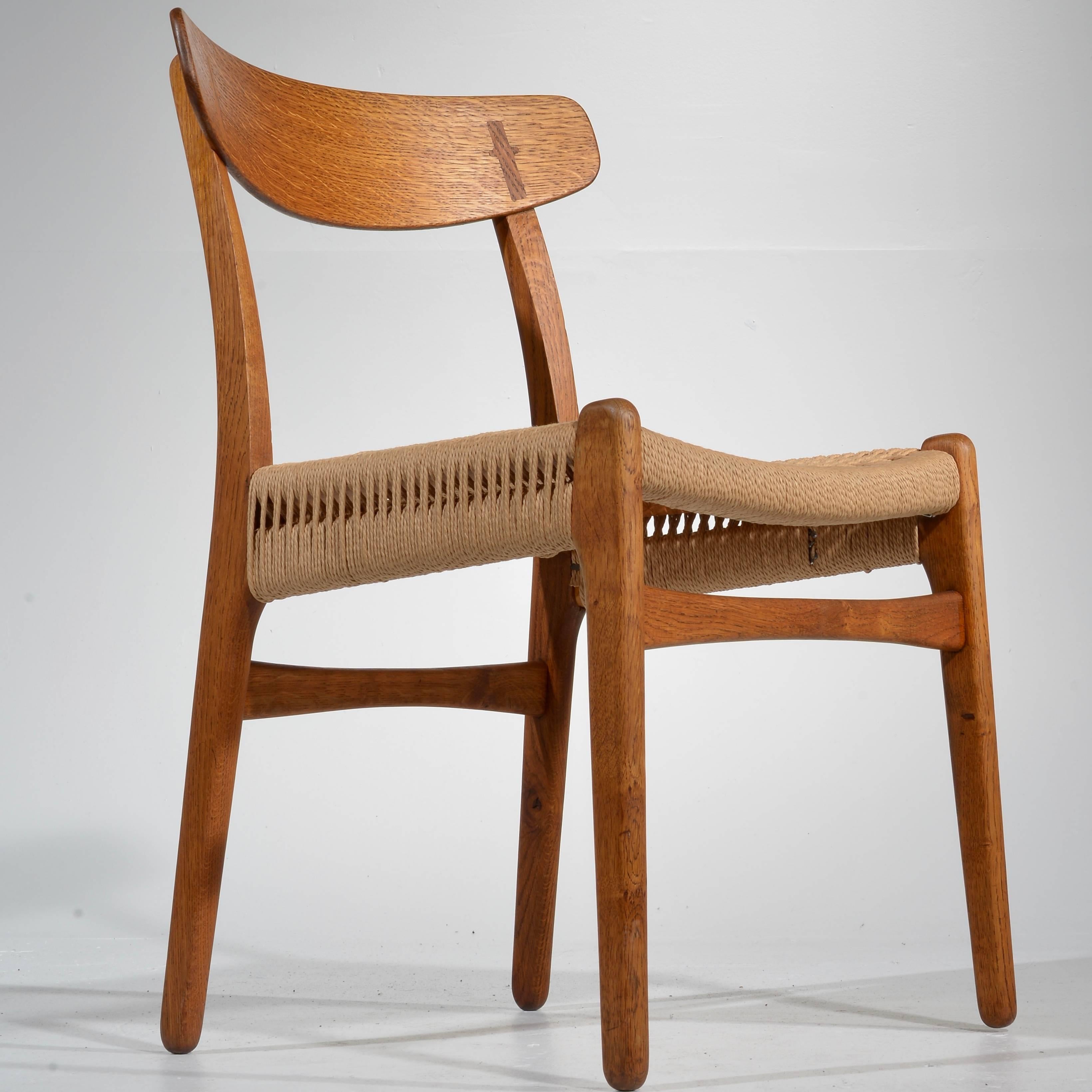 This is a beautiful and rare set of four Hans Wegner model CH-23 oak dining chairs produced by Carl Hansen & Son in Denmark. This set has been fully restored including new rope seats, re-glued joinery, and professional re-finishing.