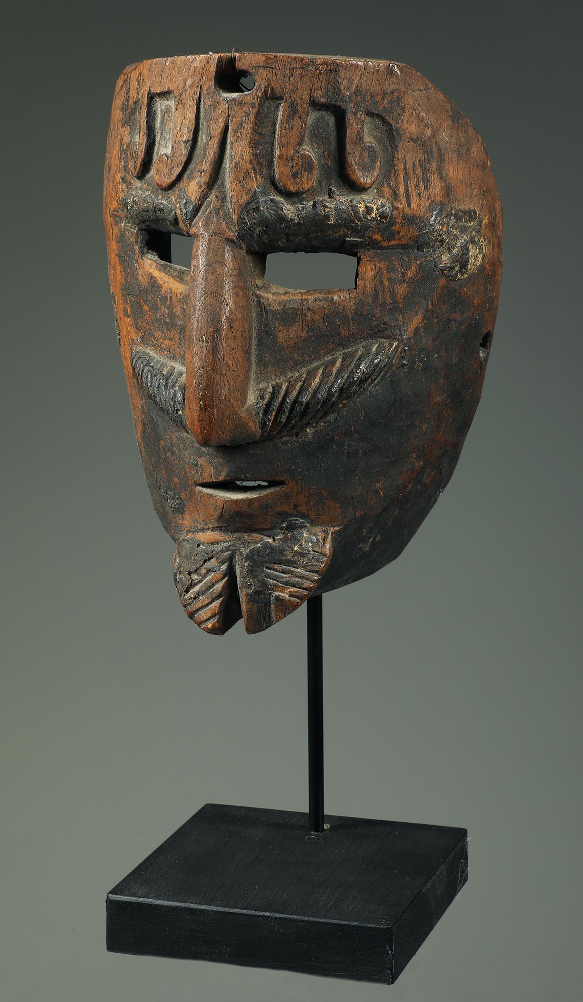 Early hardwood Mexican mask, representing a man with moustache and beard with curly hair on forehead.  Heavy staining and wear inside from traditional use, faint traces of pigments. Early to mid-20th century.  the mask is 8 inches high, on metal and