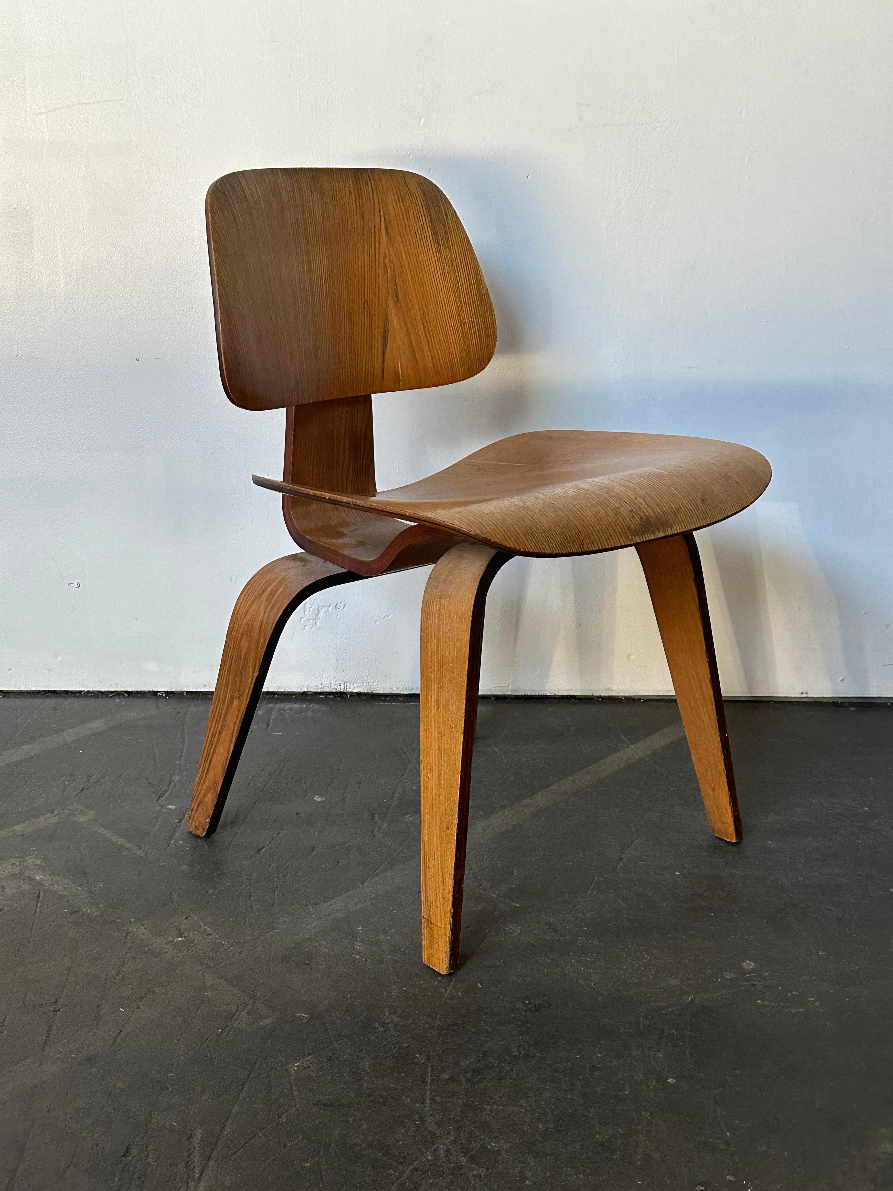 Early and original Eames DCW chair manufactured by Herman Miller. Executed in Calico Ash. All original shock mounts. 5-2-4 screw pattern under the chair indicates this is a 1950s Herman Miller production, just after Evans production period ceased.