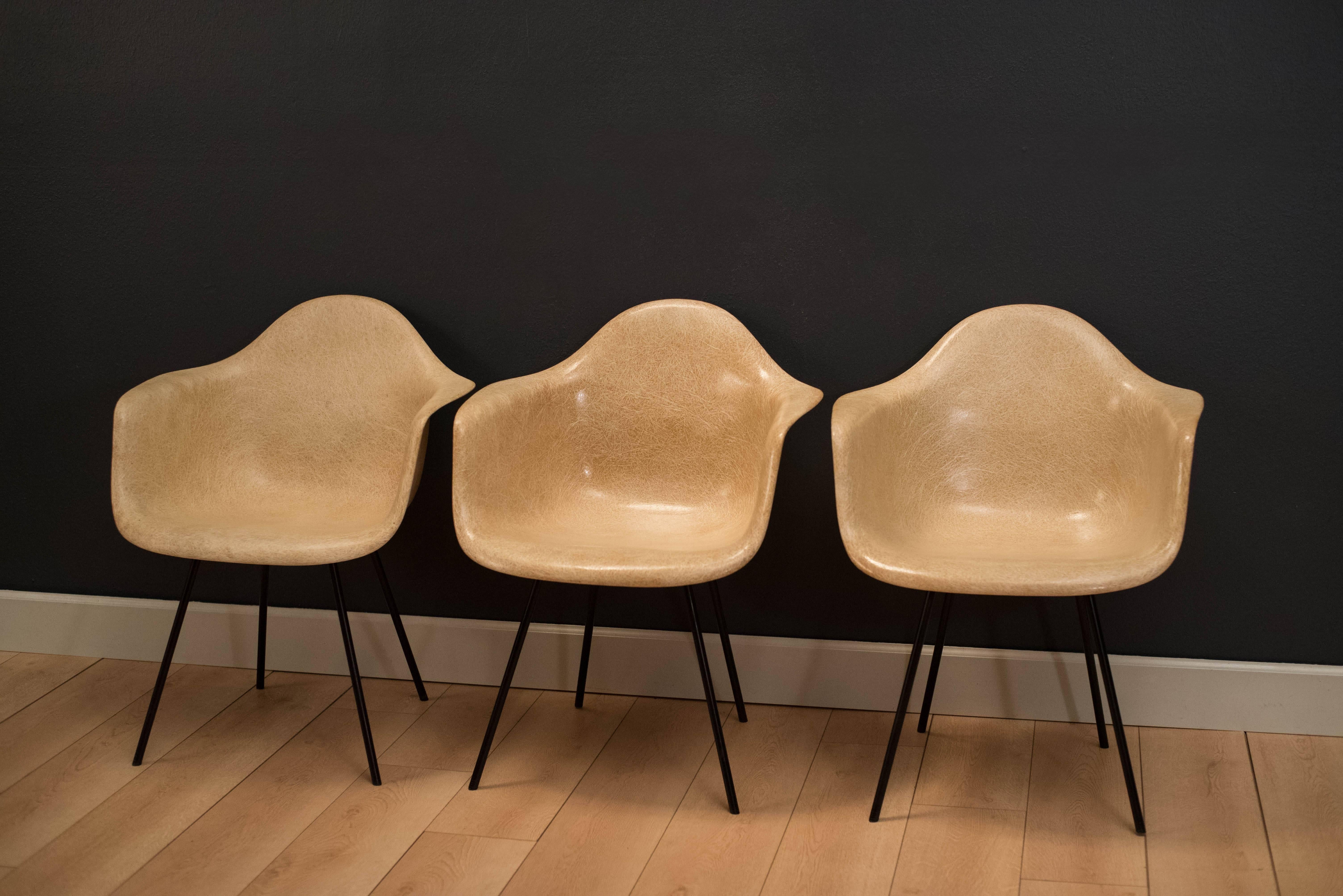 Iconic design by Ray and Charles Eames, these second generation parchment colored shell chairs have large shock mounts and original black X bases. These earlier production pieces were manufactured by Zenith Plastics.