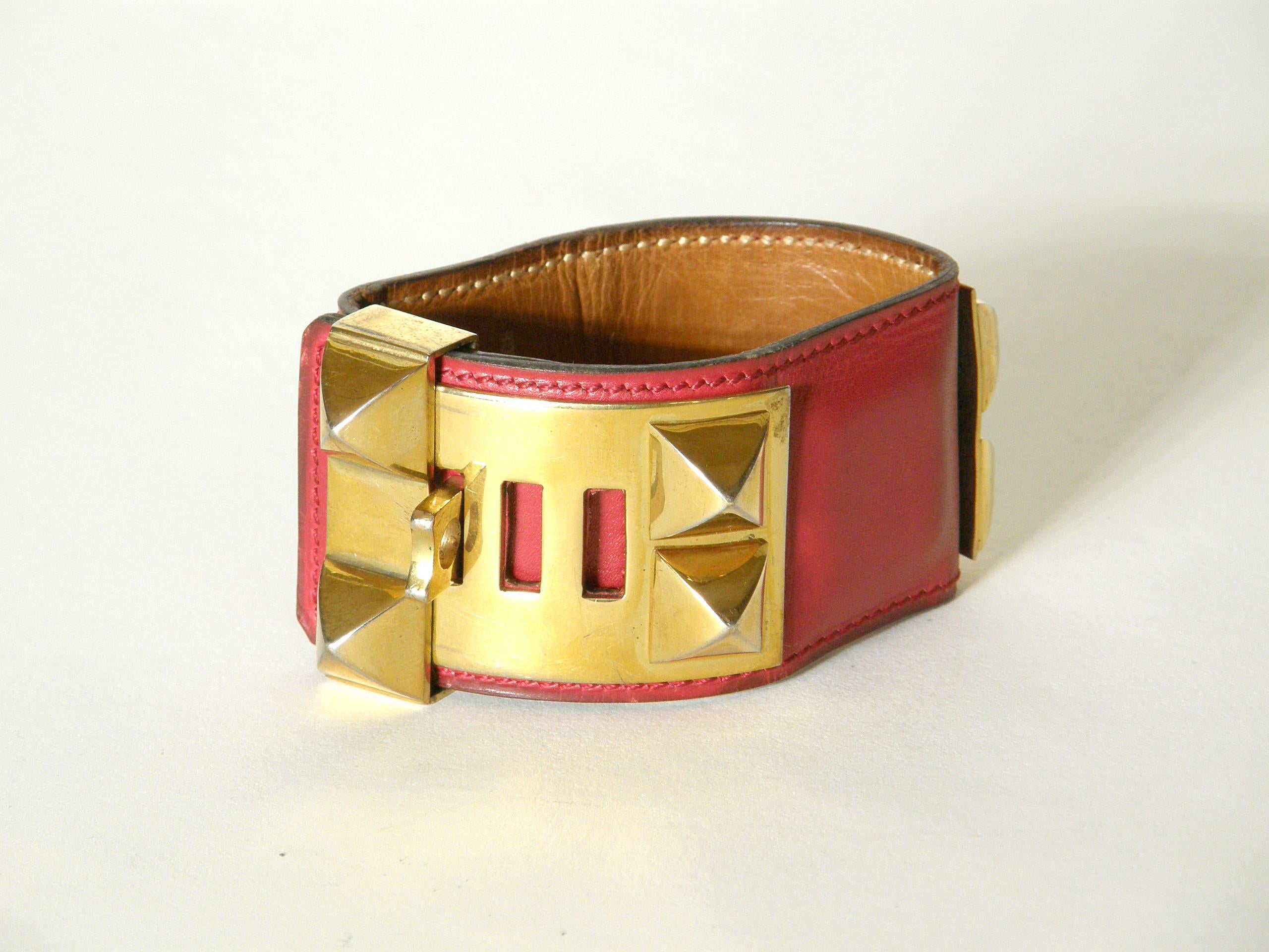 This iconic Hermès Collier de Chien cuff bracelet is made of lipstick red leather with gold plated hardware. This classic design was adapted from a custom designed dog collar made for a private client of Hermès in 1923. Due to the popularity of the