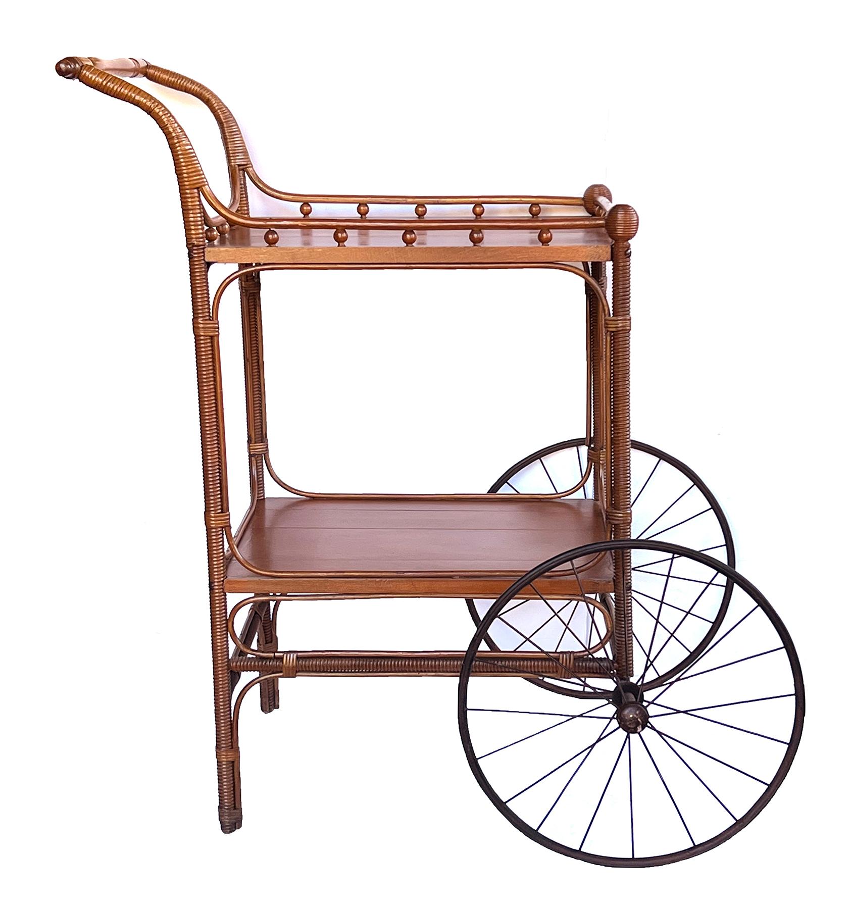 the two-wheeled drinks trolley with turned handle joining a rectangular top within an openwork gallery all raised on wicker-wrapped supports joining a lower shelf; The Heywood Furniture Co. began in 1826 making wicker and rattan furniture. In 1897,