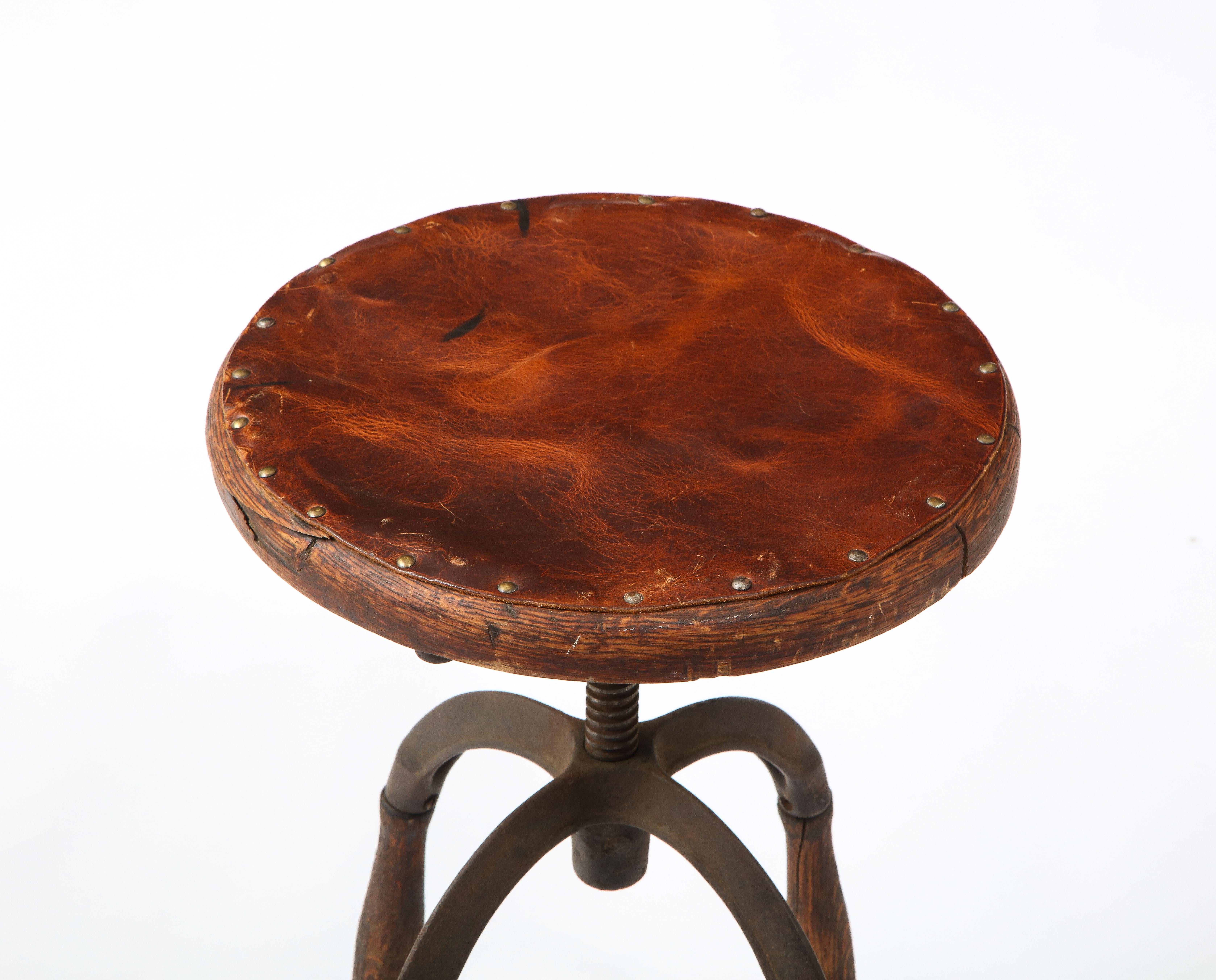 Industrial stool in cast iron and carved oak, it adjusts via an acme thread and the seat leather-covered wood.