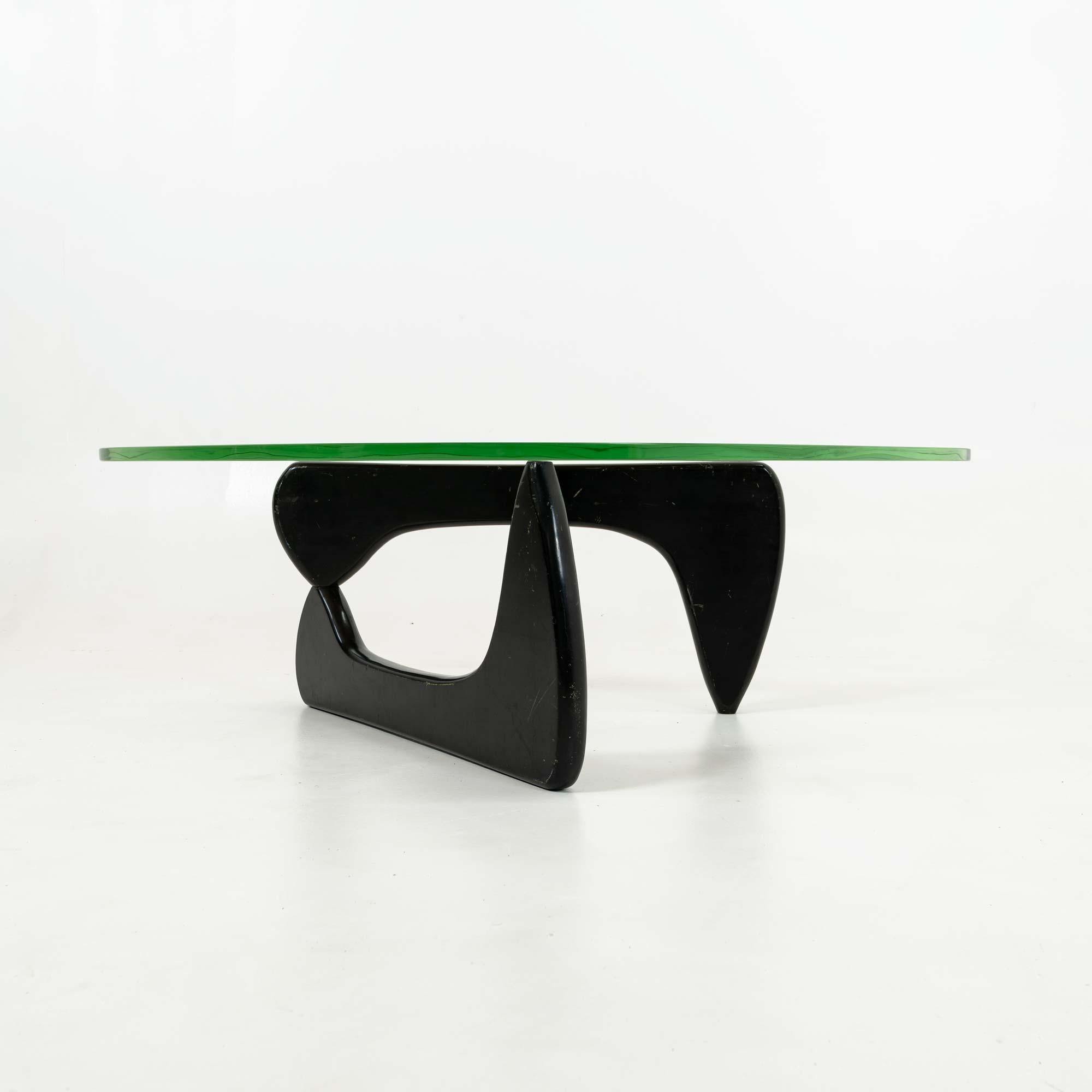 An early Noguchi IN50 coffee table with the original green glass, early 1950s. black base with pantina matching age, straight pin ( later pins has locking fins). moderate scratches  on the glass, as seen in the last few photos

Authenticity- this