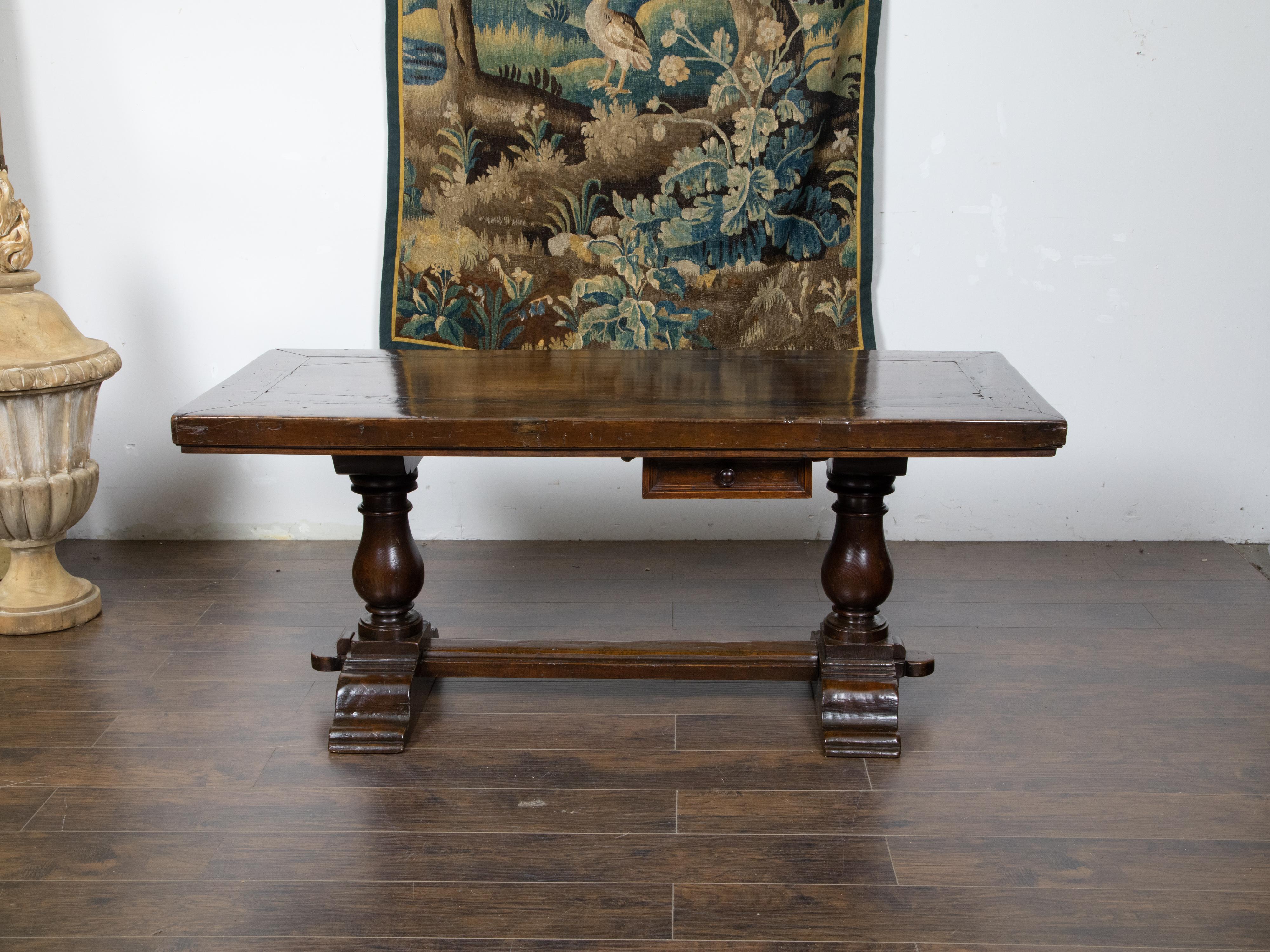 An Italian walnut table from the 19th century, with trestle base, turned legs, cross stretcher and single drawer. Created in Italy during the 19th century, this walnut table features a rectangular top with nicely weathered appearance, sitting above