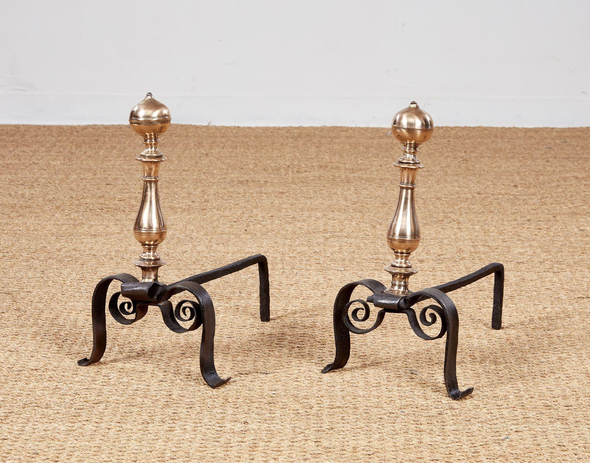 Lovely pair of early Italian baroque bronze and wrought iron andirons having suppressed ball finials over balustrade shafts and standing on elegant high scrolled legs ending in flared feet.  Circa 1670.