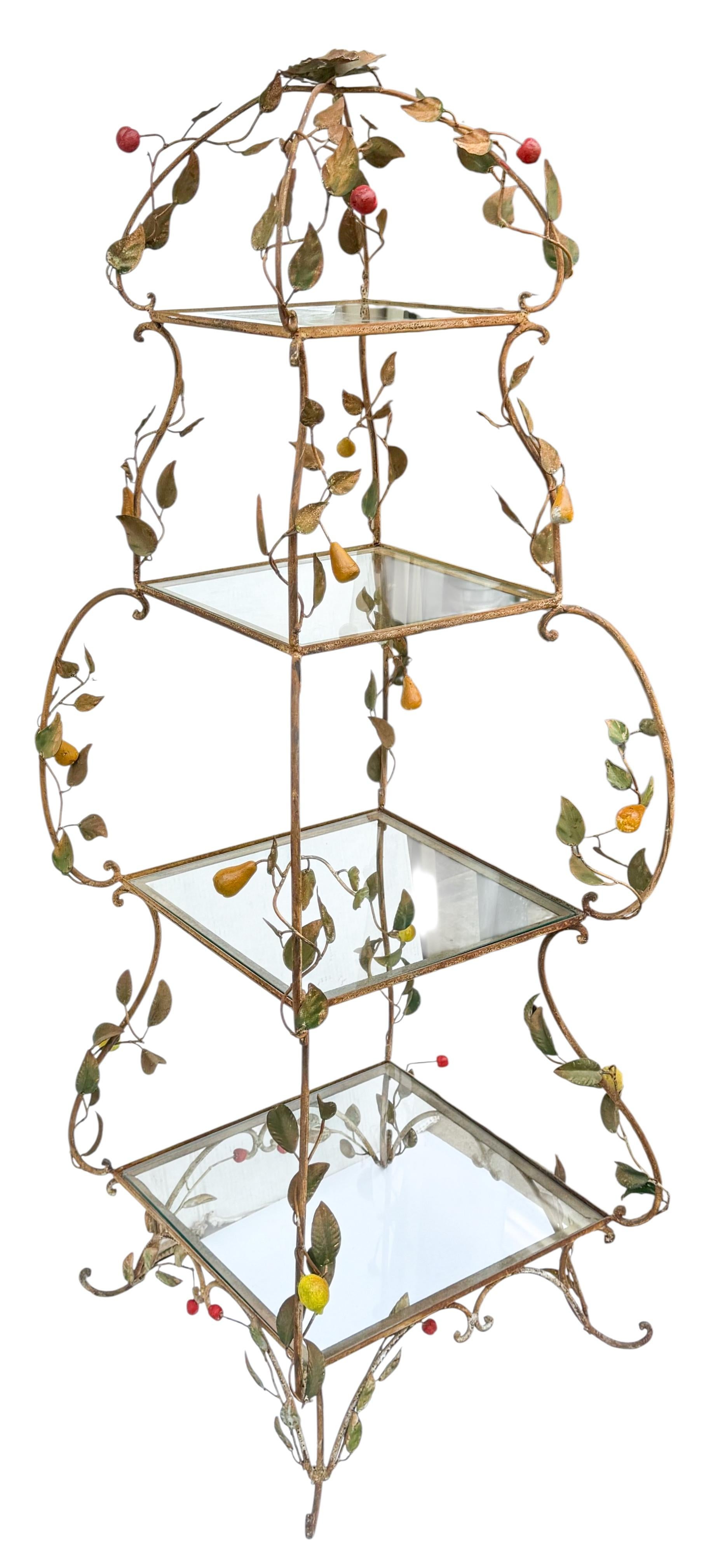 This is an early Italian tole etagere with glass shelves. It features cascading greenery and fruit. It was probably once used outside as it does show wear to the greenery and frame. It is a very charming piece. Shelf distances are 8”, 10”, 13”, and