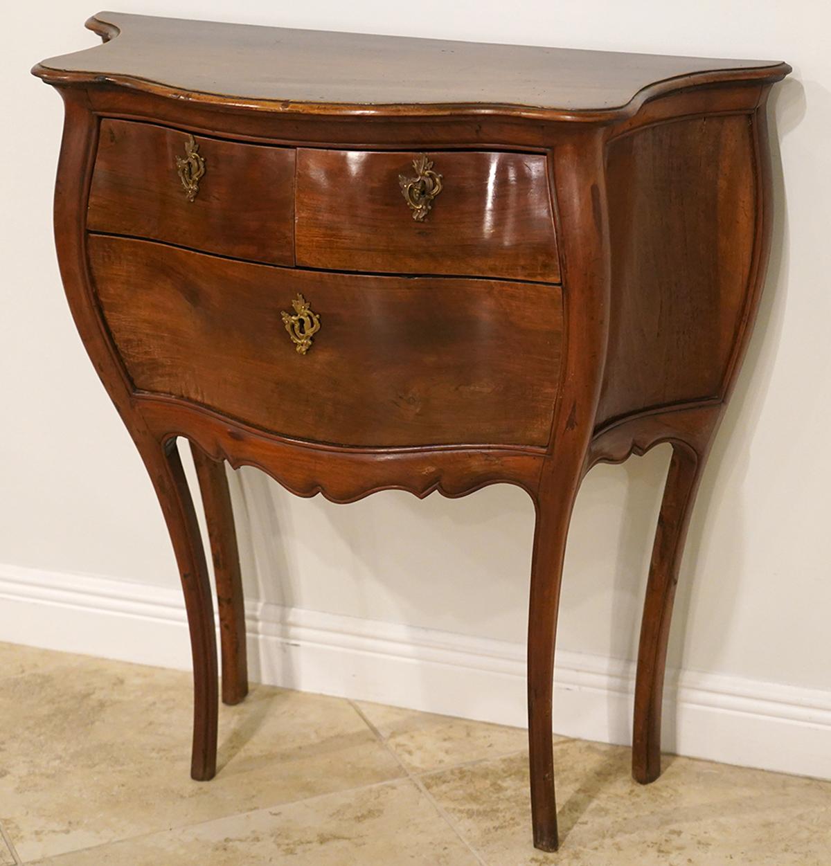 Strikingly elegant lines characterizes this lovely Italian transitional rococo bombe commode. It features a serpentine shaped top following the bombe design above two short drawers and one long mounted with rococo foliate bronze escutcheons. The