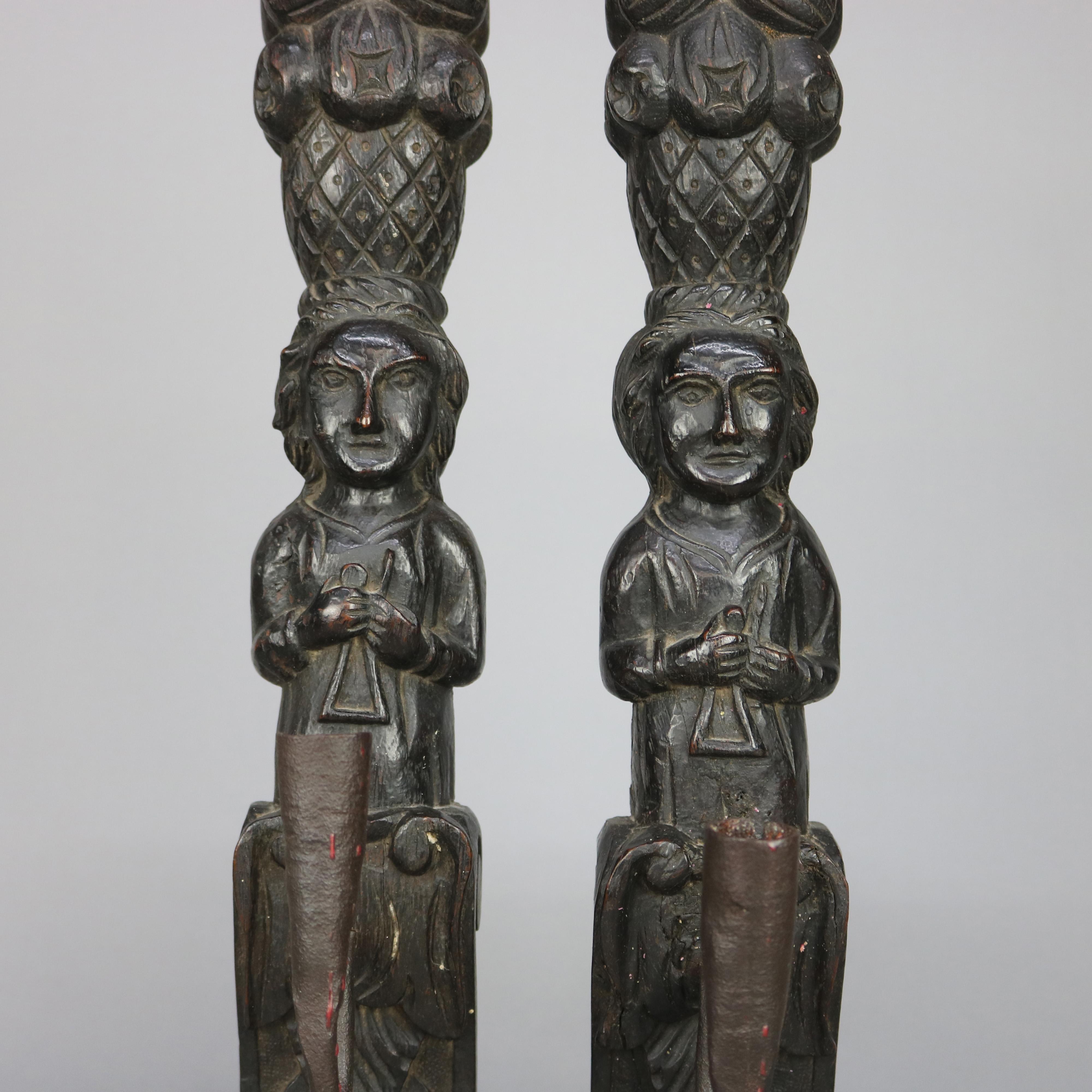 An antique set of early Jacobean Tudor candle wall sconces offer carved oak panels in the form of tribal food gatherers having baskets of fruits with C-scroll handwrought iron arms terminating in candle sockets, 18th century.

Measures: 20.5