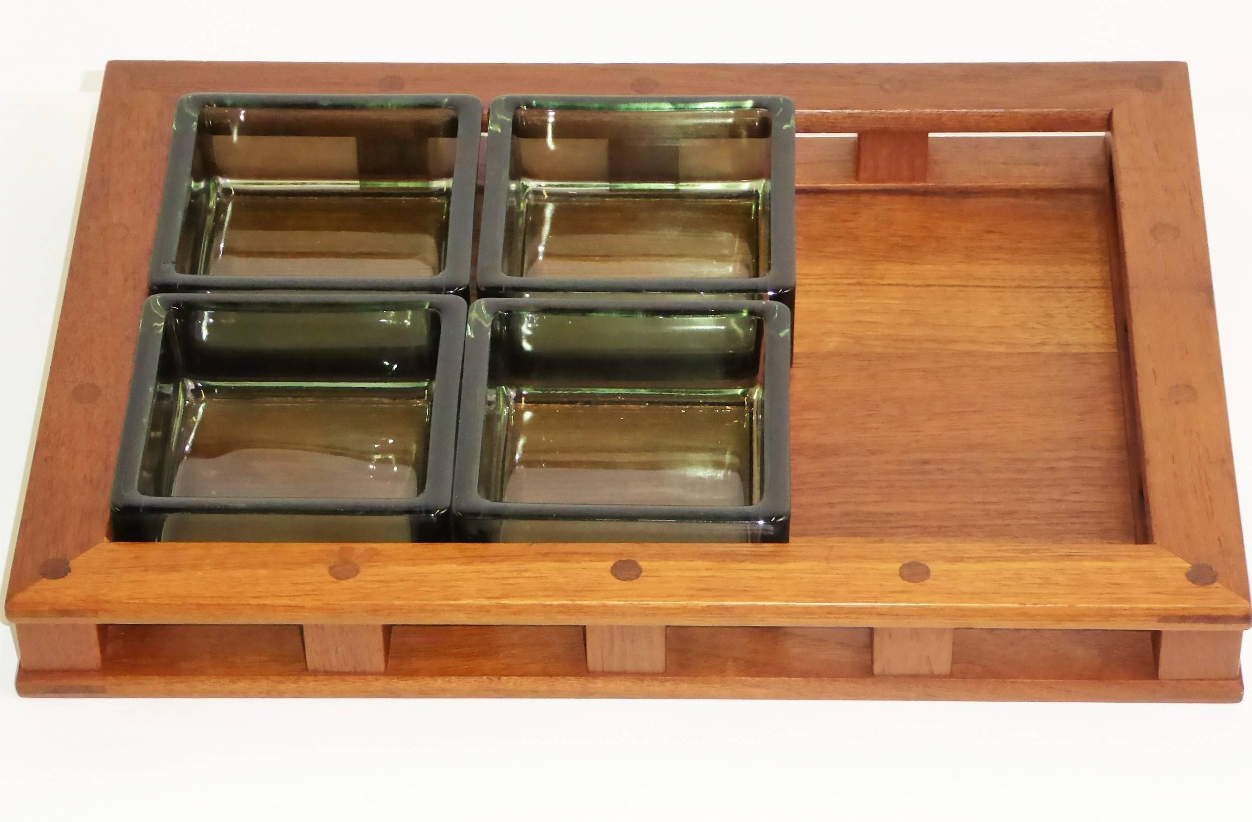 This 1960s Jens Quistgaard designed teak wood serving tray with four thick green glass inserts is from Dansk Designs and made in Denmark. The teak wood of the earlier, Danish-made pieces by Quistgaard was of a higher quality than the later pieces.