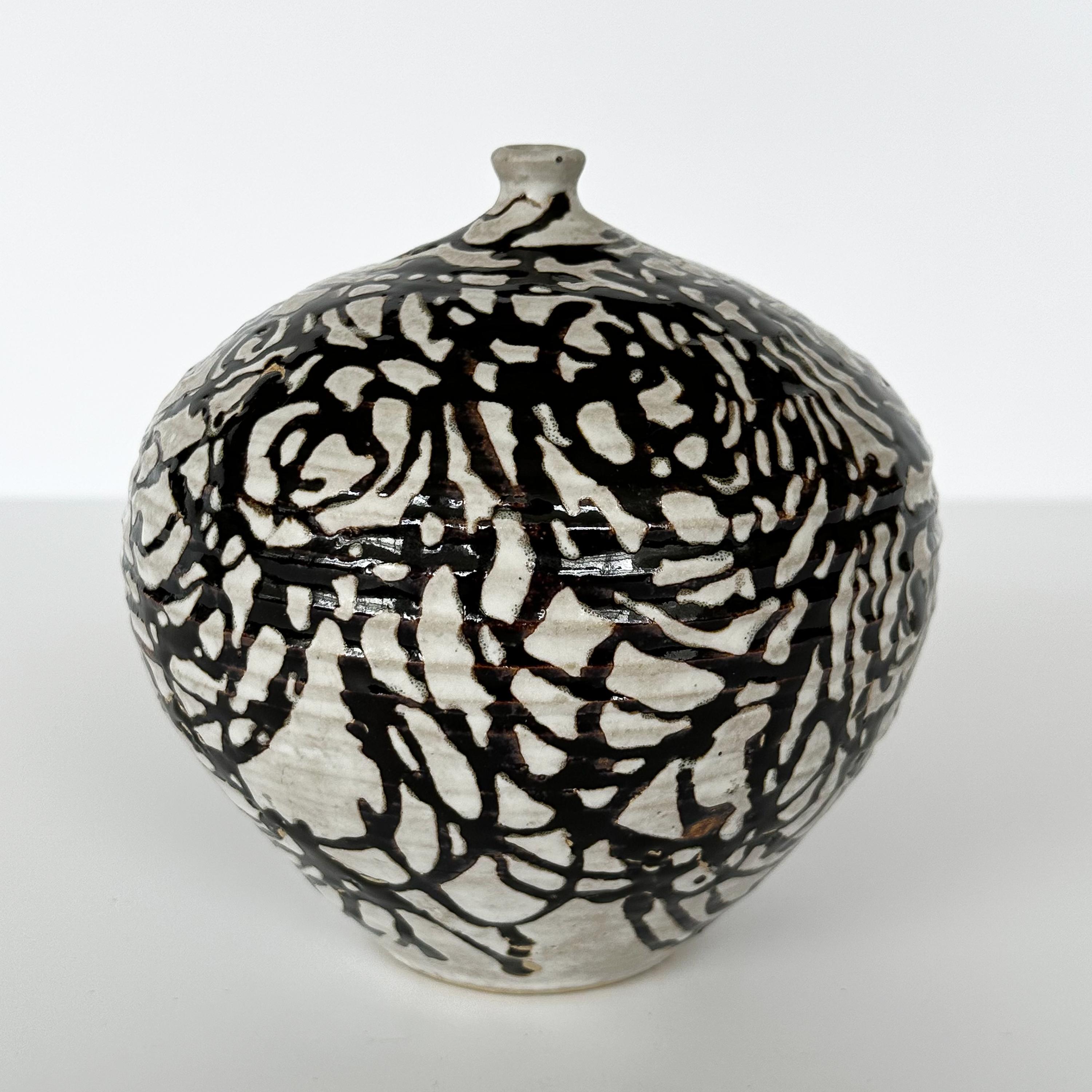 A rare / early JT Abernathy (American b. 1923) studio pottery weed vase, circa 1960s. This vase features a matte white background overlaid with a dark chocolate brown glaze in a graphic loose swirling abstract design. The glaze created almost an