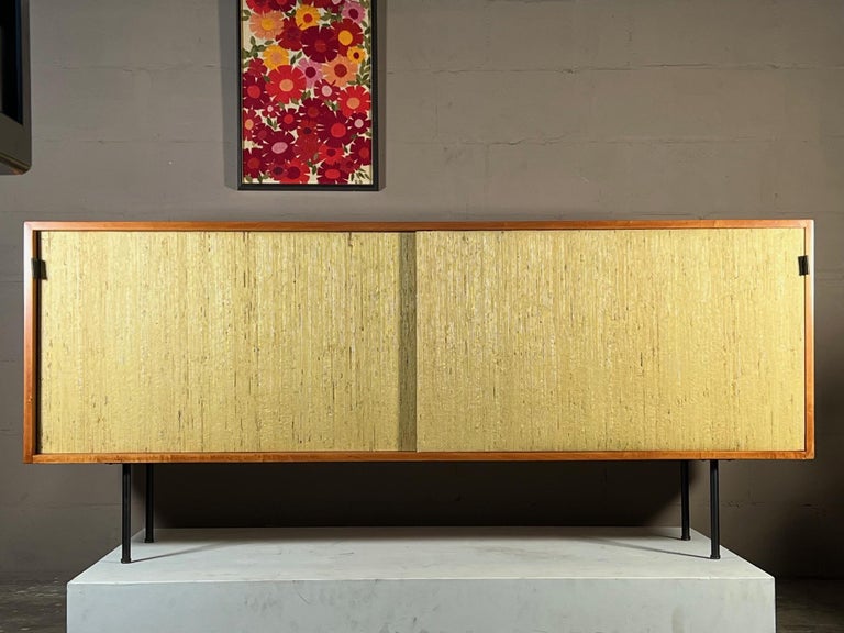 An early and classic Florence Knoll/Knoll credenza with grasscloth front. Original steel tubular legs, oak shelves. Beautifully restored and ready to be used for many years to come.