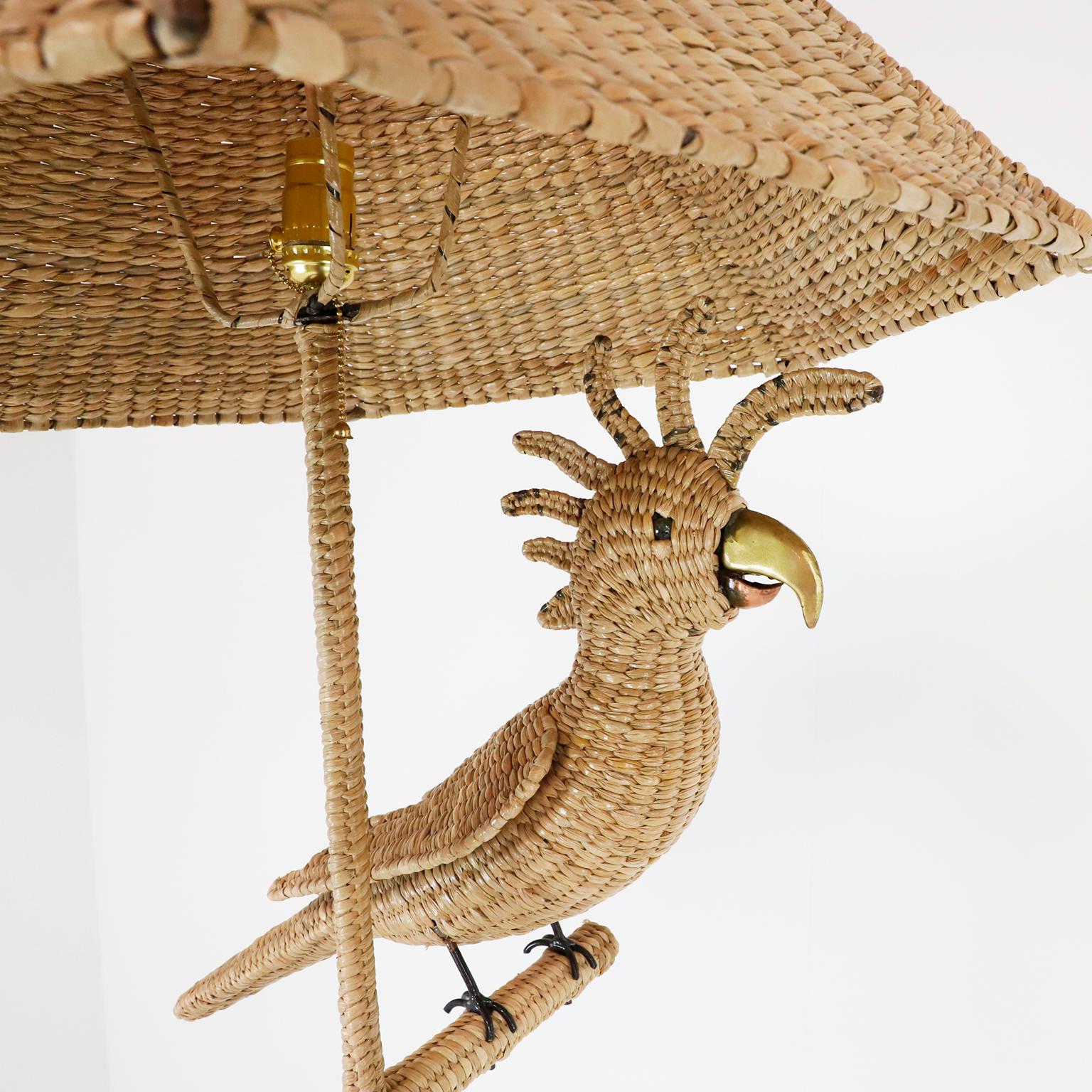 Circa 1970. We offer this exceptional floor lamp by the highly acclaimed Mexican artist and sculptor Mario Lopez Torres, the enormous metal frame and chuspata woven design stands at over 1.7 m. tall and features the large perched macaw. The button