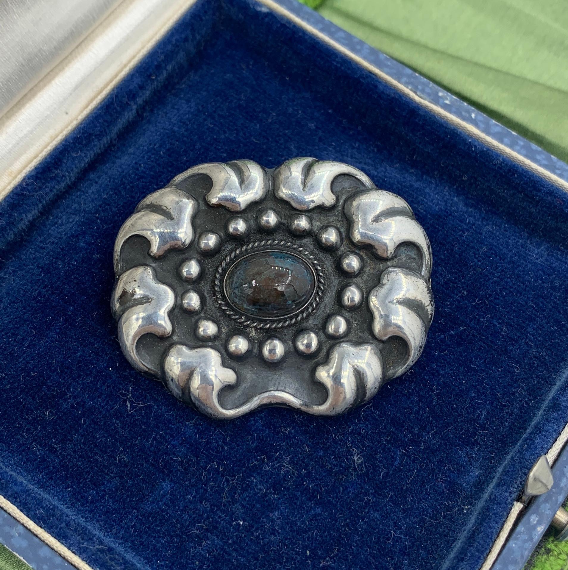 This is the gorgeous early Marius Hammer Art Nouveau silver pin brooch in the form of a flower set with a stunning blue-grey Labradorite gem. The brooch has the mark of Marius Hammer of Norway and 830S for 830 silver.
This pin is a wonderful example