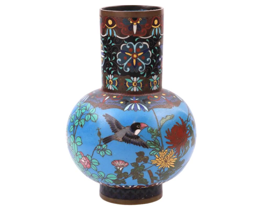 An antique Japanese copper vase with cloisonne enamel design against a bright turquoise background. Meiji period.

The vase is of a bulbous shape with a long fluted neck. Birds flying among flower branches are depicted on the body of the vase. The