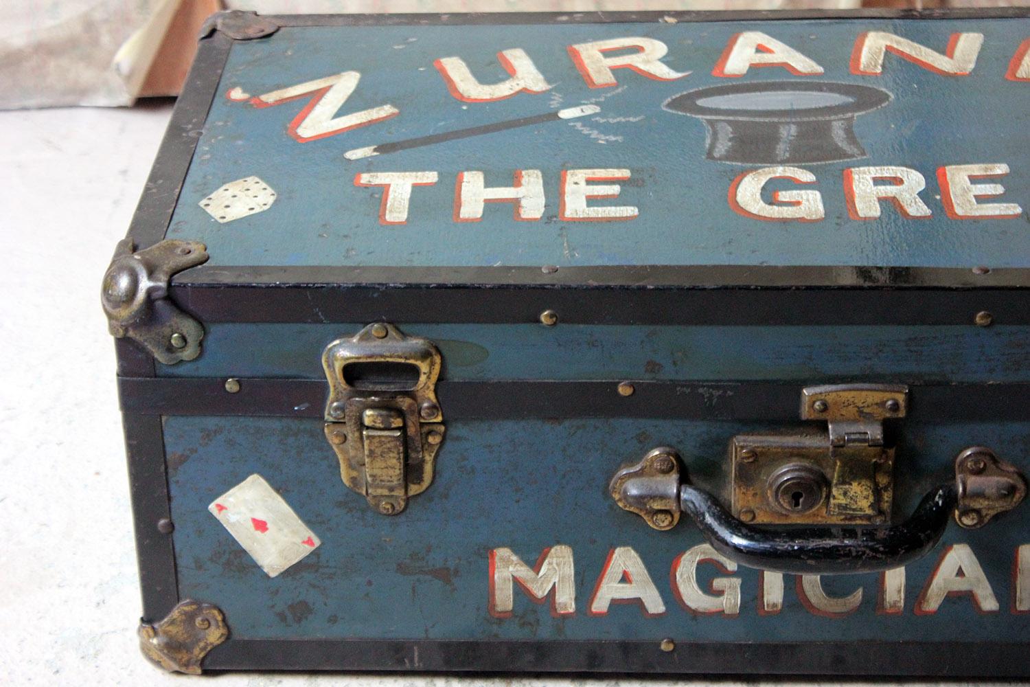 The hand painted magicians travelling suitcase painted in teal with a top hat, wand, die, three magic rings, balloons and playing cards, and signwritten 