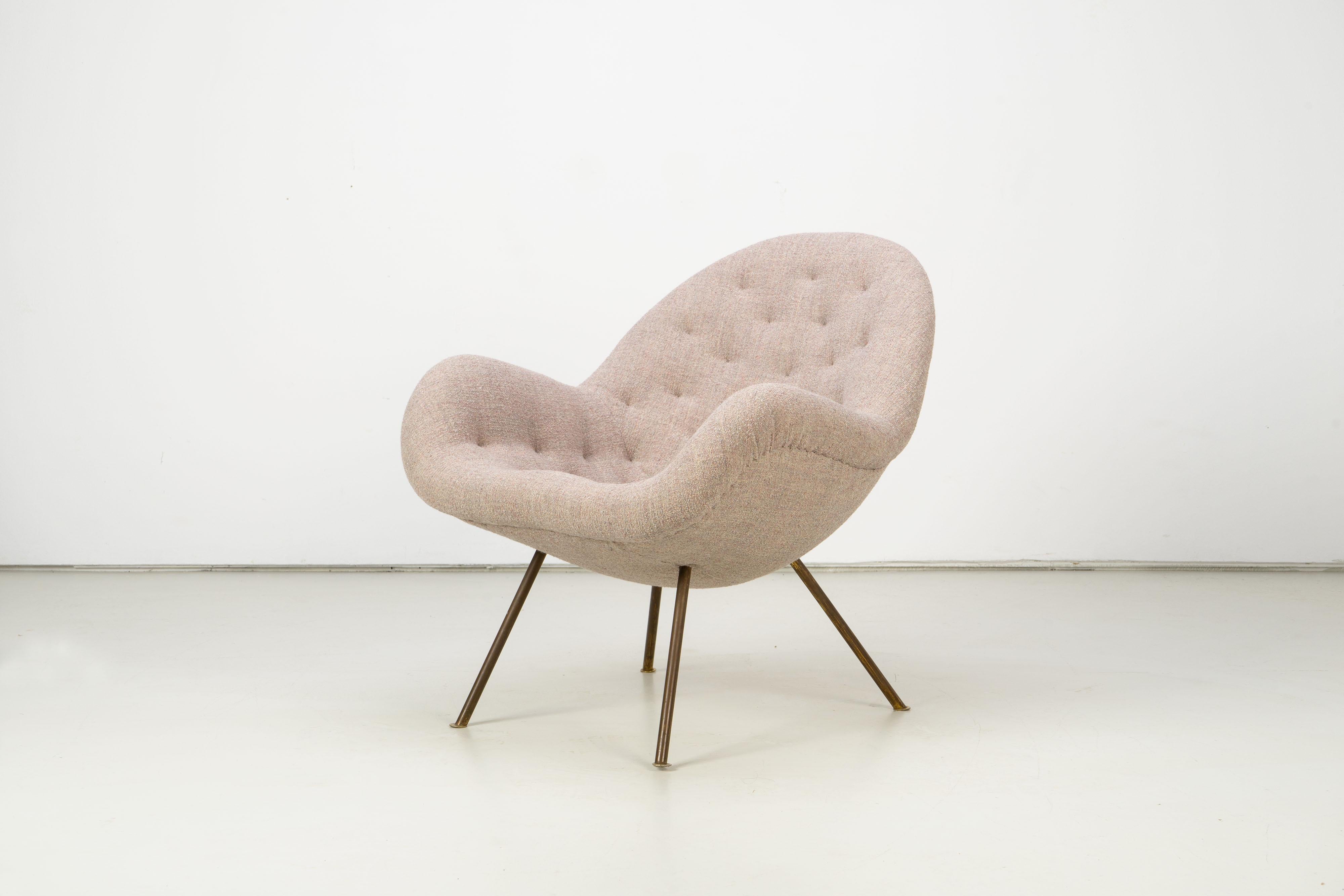 Beautiful lounge chair with tufted upholstery and patinated brass legs from the early 1950s. The chair has been newly upholstered with the fabric 