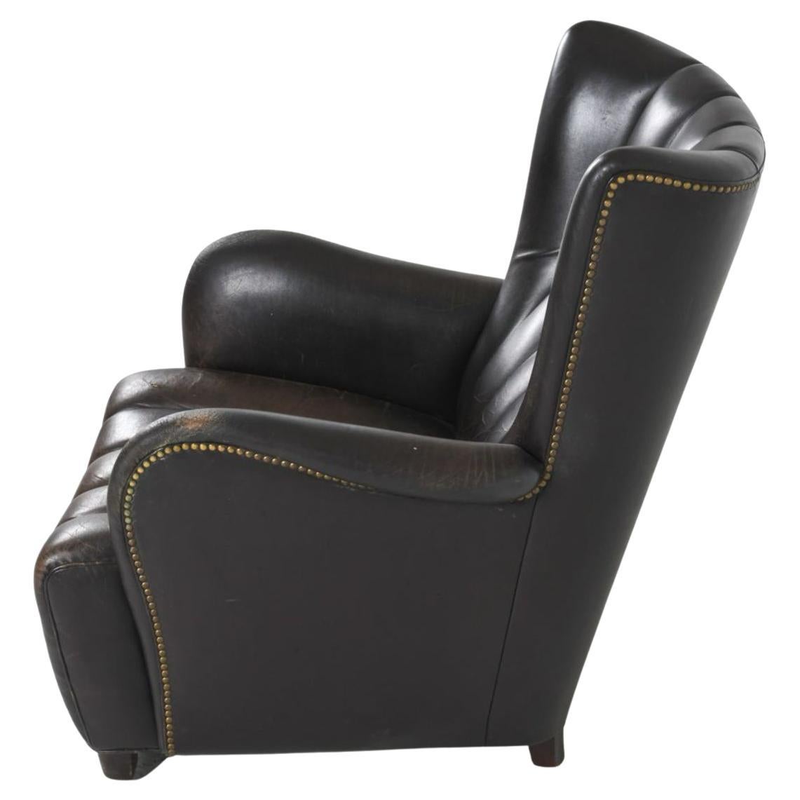 Sedia da salotto scandinava di metà secolo, in pelle canalizzata e ottone, nello stile di Fritz-Brass. Sedia facile che presenta un'imbottitura a canali sullo schienale e sulla seduta e gambe in Beeche. Ha chiodi da tappezzeria in ottone con una