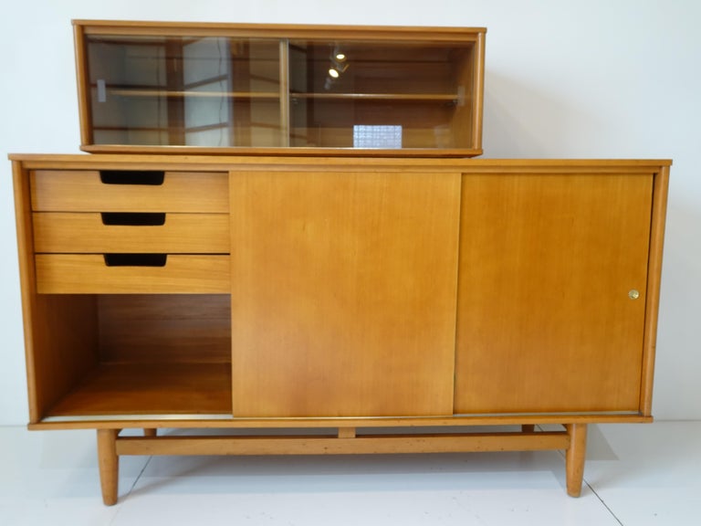 A two piece mahogany sideboard / credenza with rare upper cabinet having two wooden shelves and sliding glass doors. The lower cabinet has three sliding doors with drawers to both sides and three wooden center shelves. This is an well crafted early