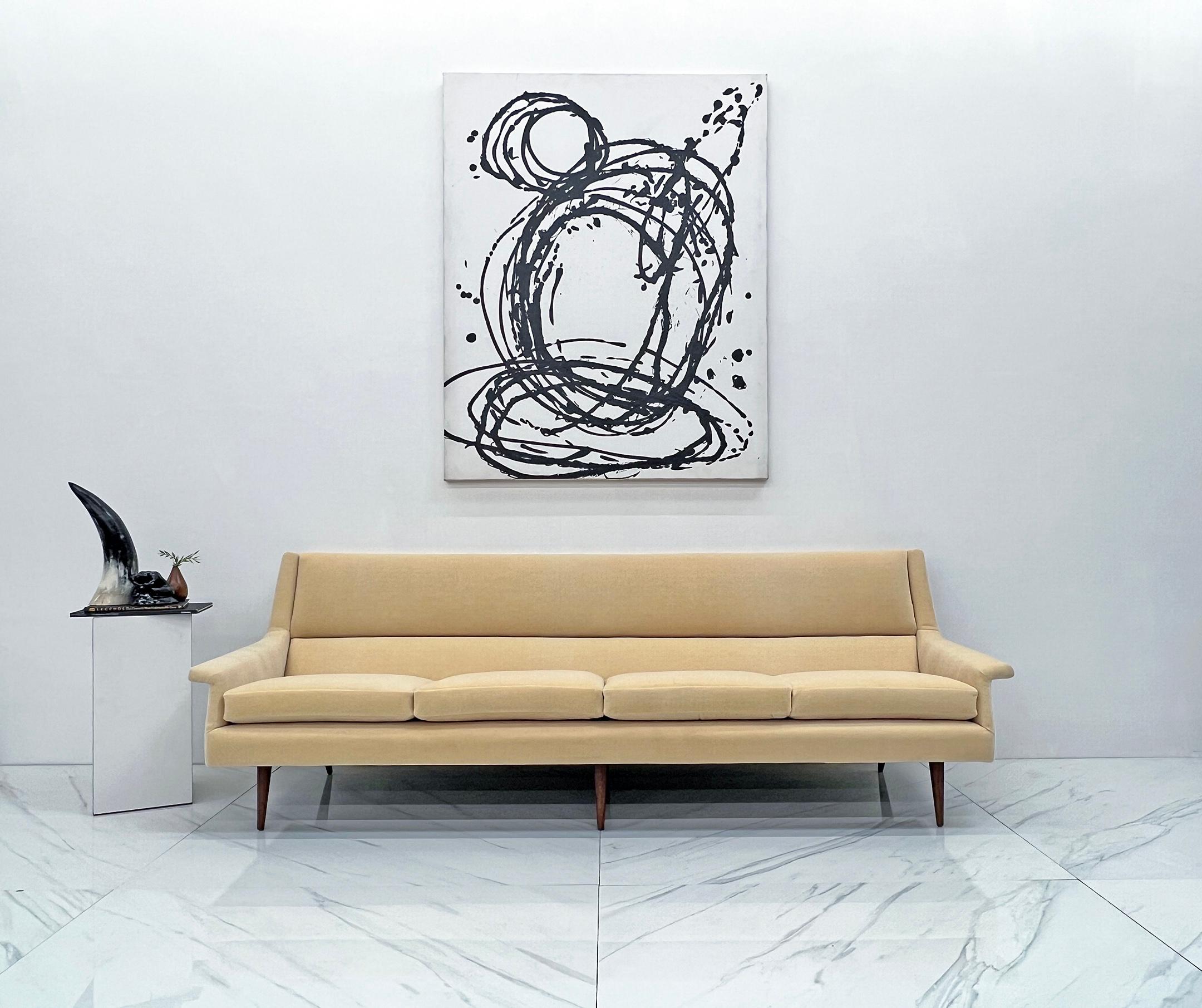 This sofa is absolutely stunning. Designed in the late 1950's by Milo Baughman, this sofa epitomizes chic mid century modern at its finest. This tuxedo style sofa features clean lines, defined arms, and 6 legs that splay out in the back in an