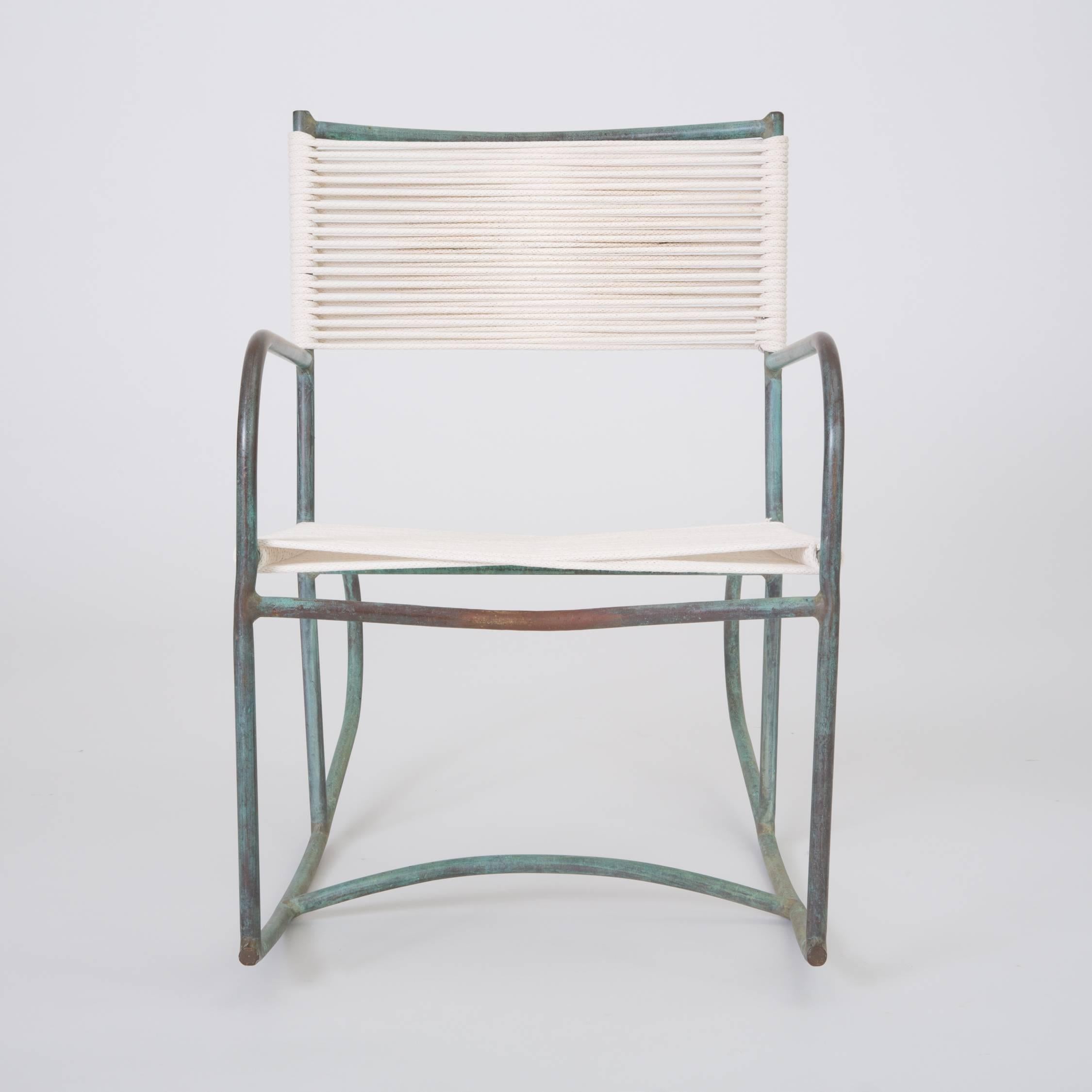 A late 1940s or early 1950s Walter Lamb rocking chair predating or from the early days of his partnership with Brown Jordan. The chair has a frame in tubular bronze with the verdigris patina that distinguishes his designs. Two runners with bowed