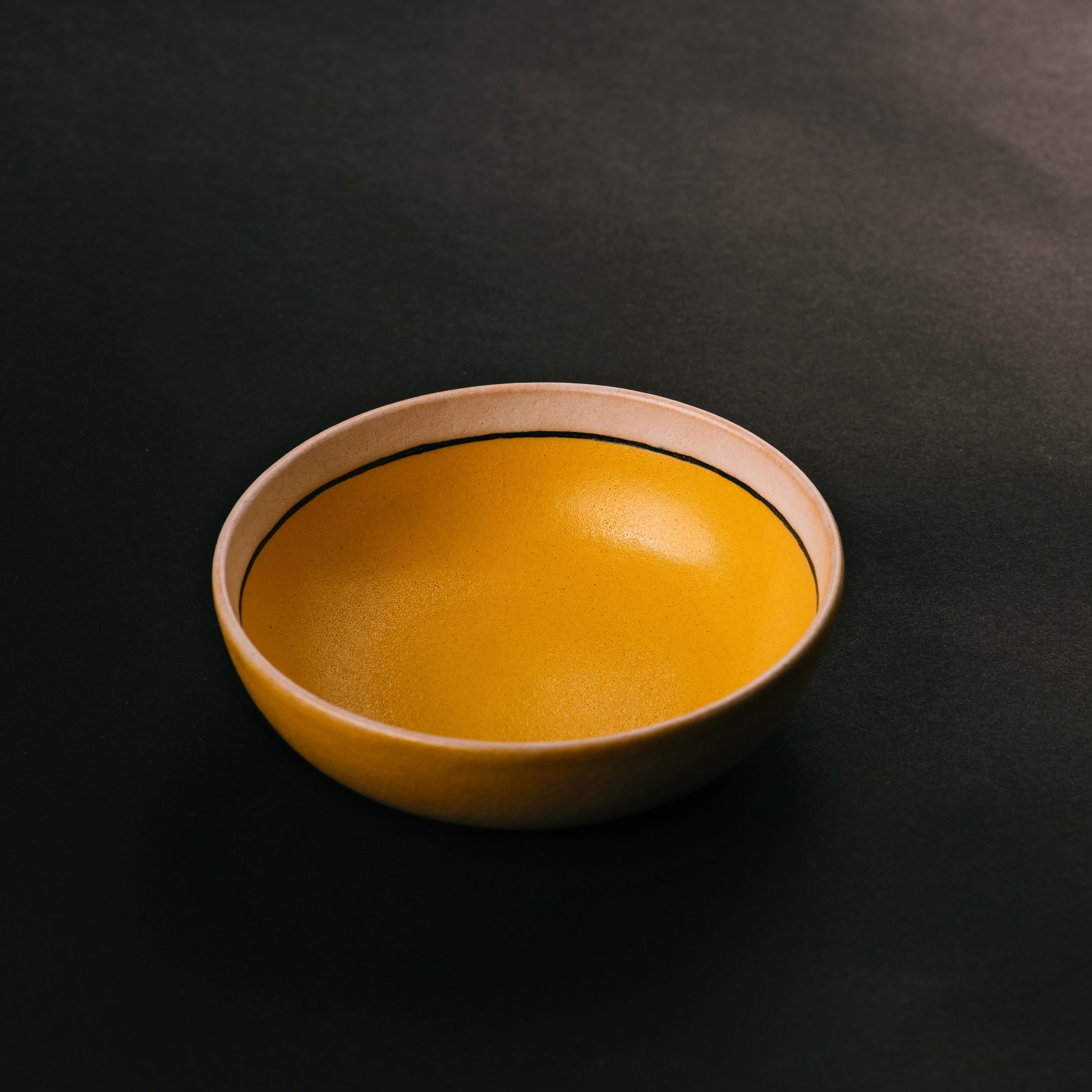 Arts and Crafts movement, petite ceramic bowl by Fannie Levine for Saturday Evening Girls. This early modernist design was created using the cuerda seca technique, its soft white and yellow glazes separated by a thin black border. Signed and dated