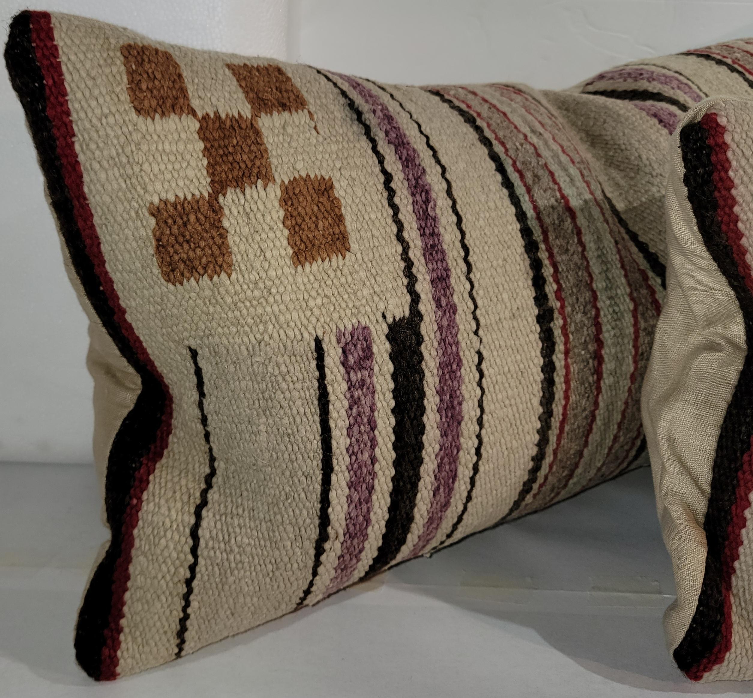 Early 20thc Navajo Indian weaving saddle blanket bolster pillows. The backings are in a cotton linen and the inserts are down & feather fill.Sold as a pair.