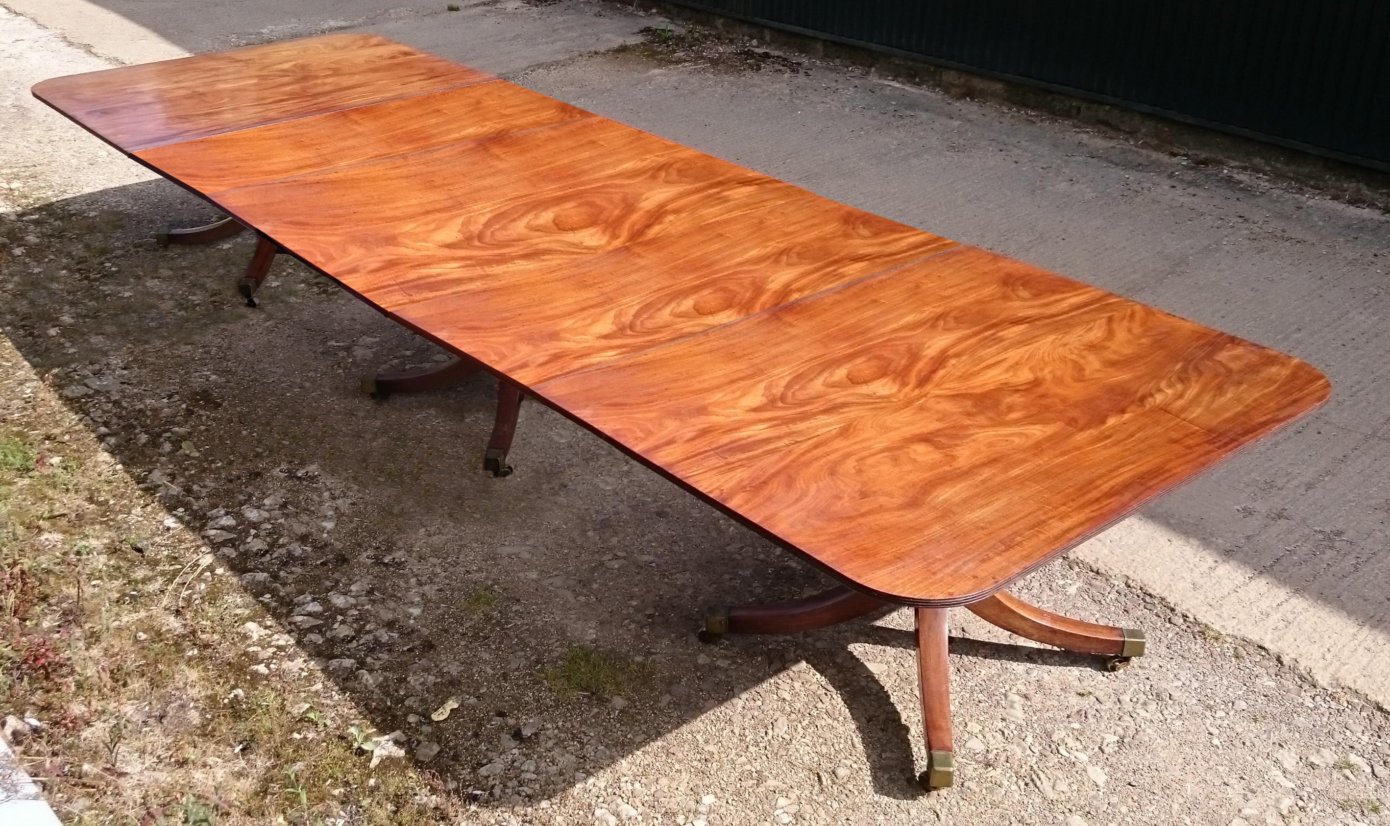 Early 19th century mahogany antique dining table standing on three pedestals, each with four splay base. This is a large scale table which has faded to a desirable golden brown honey colour. The bases are a well balanced design and are of strong