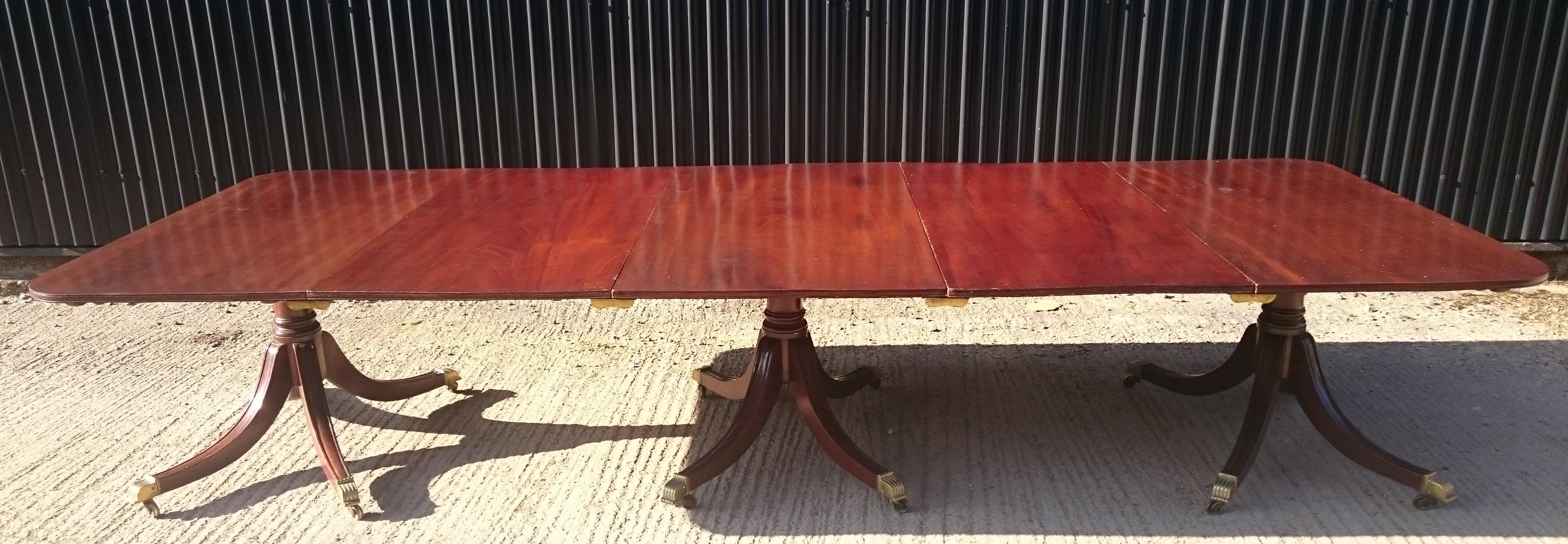 Early 19th century Georgian mahogany three-pedestal antique dining table. This is an elegant table made of large sheets of very Fine quality solid mahogany. The edge of the top and legs are delicately moulded, the latter ending with interesting gilt