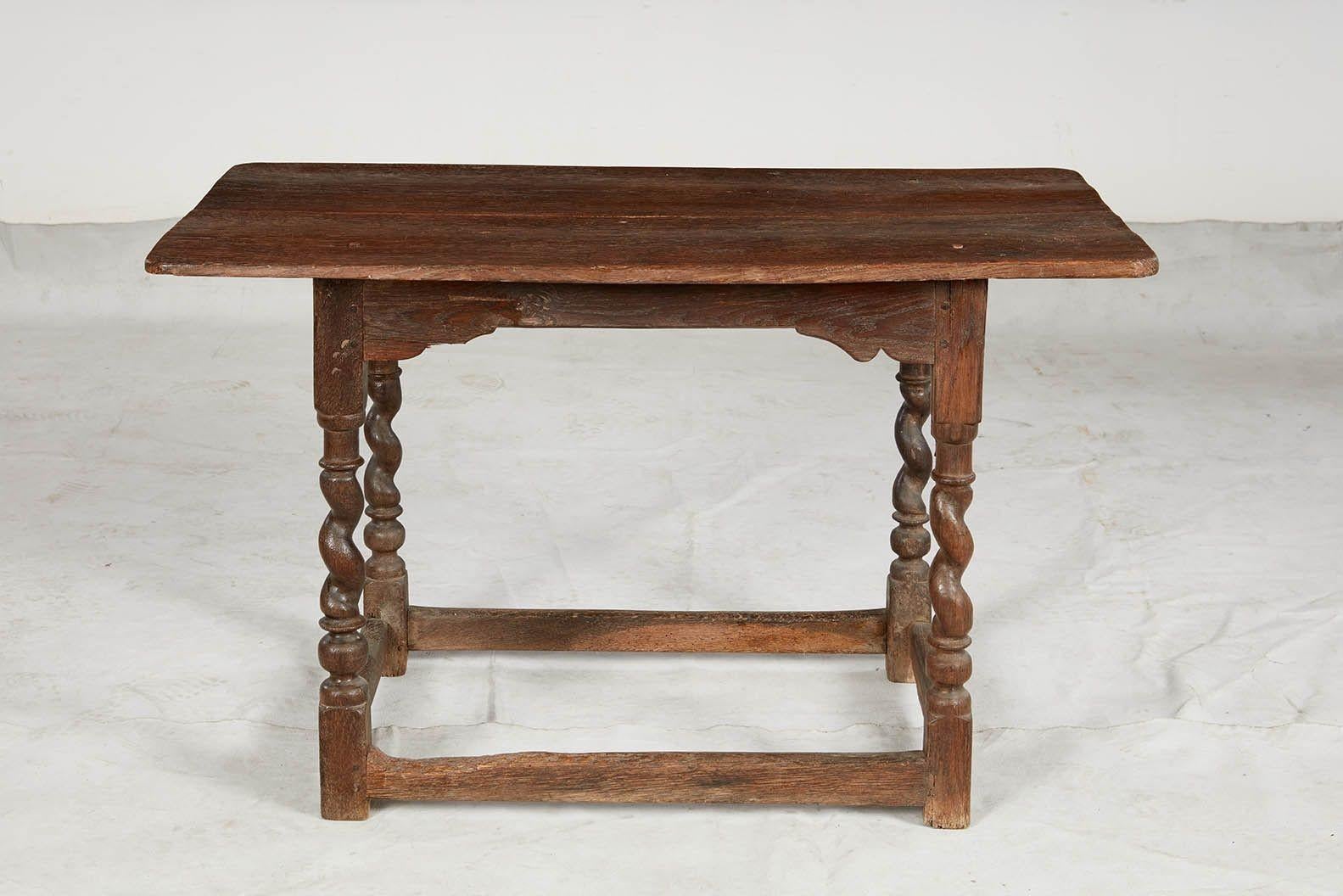 A 17th century English oak center table with two plank top and eased corners over bracketed aprons, standing on barley twist legs joined by a low square section box stretcher. Scrubbed surface retaining original lovely mellow 