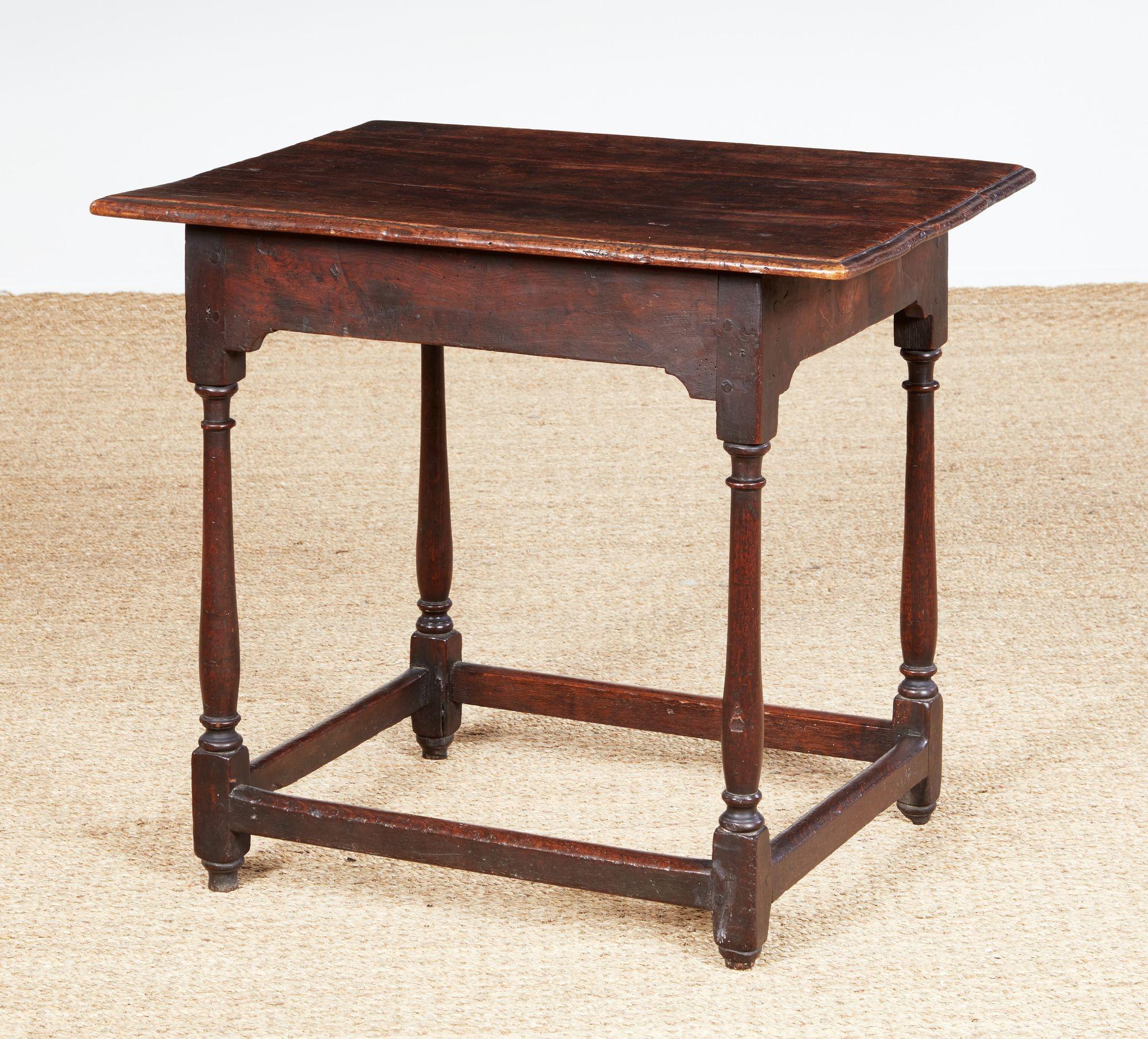 Une table traditionnelle anglaise du début du 18e siècle avec un plateau en planches à bord mouluré sur un fin tablier aux coins intérieurs façonnés reposant sur quatre pieds tournés en balustre reliés par un châssis à section rectangulaire. Forme