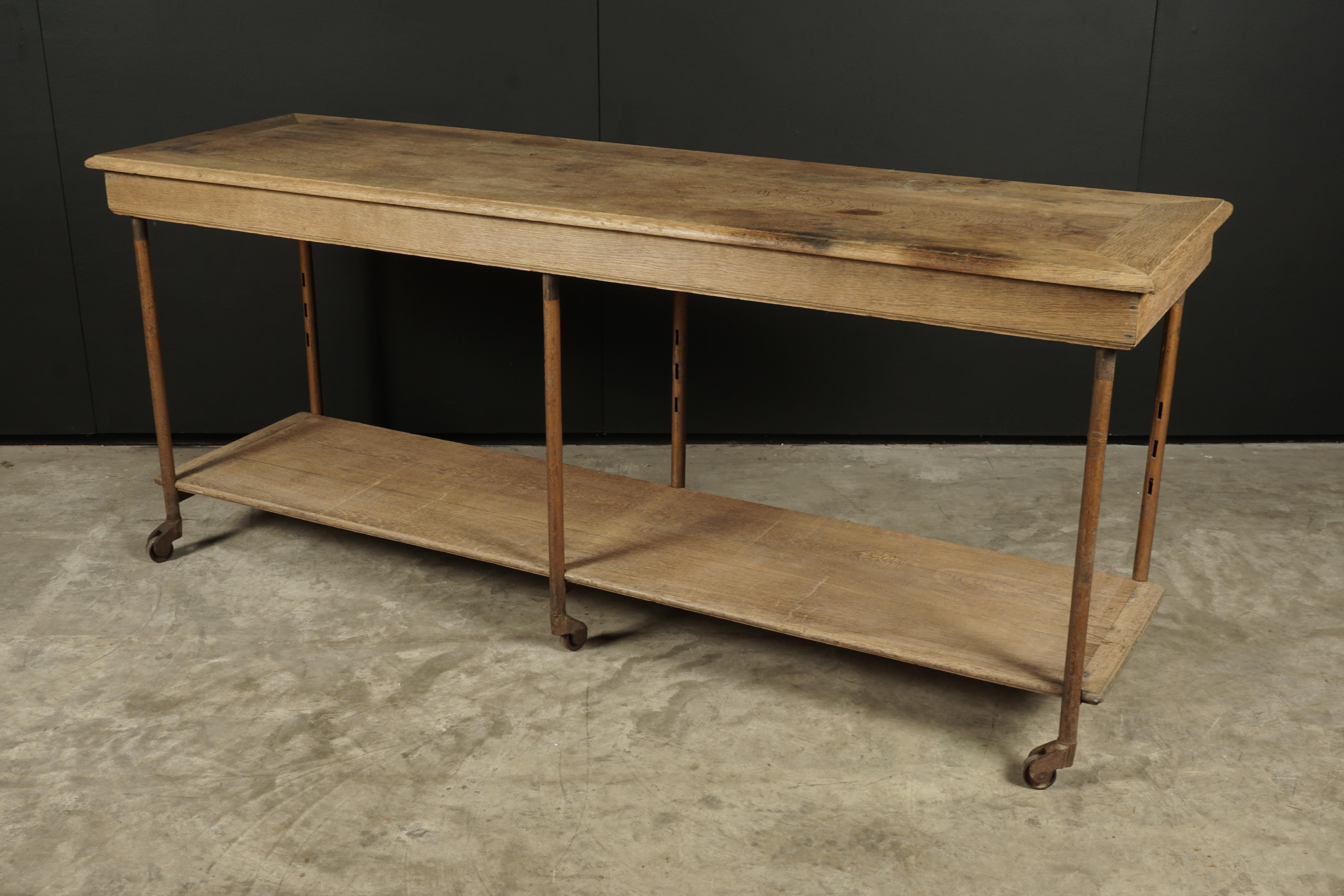 Early oak haberdashery console table from France, circa 1900. Solid oak with a frame in steel. Original casters on feet.