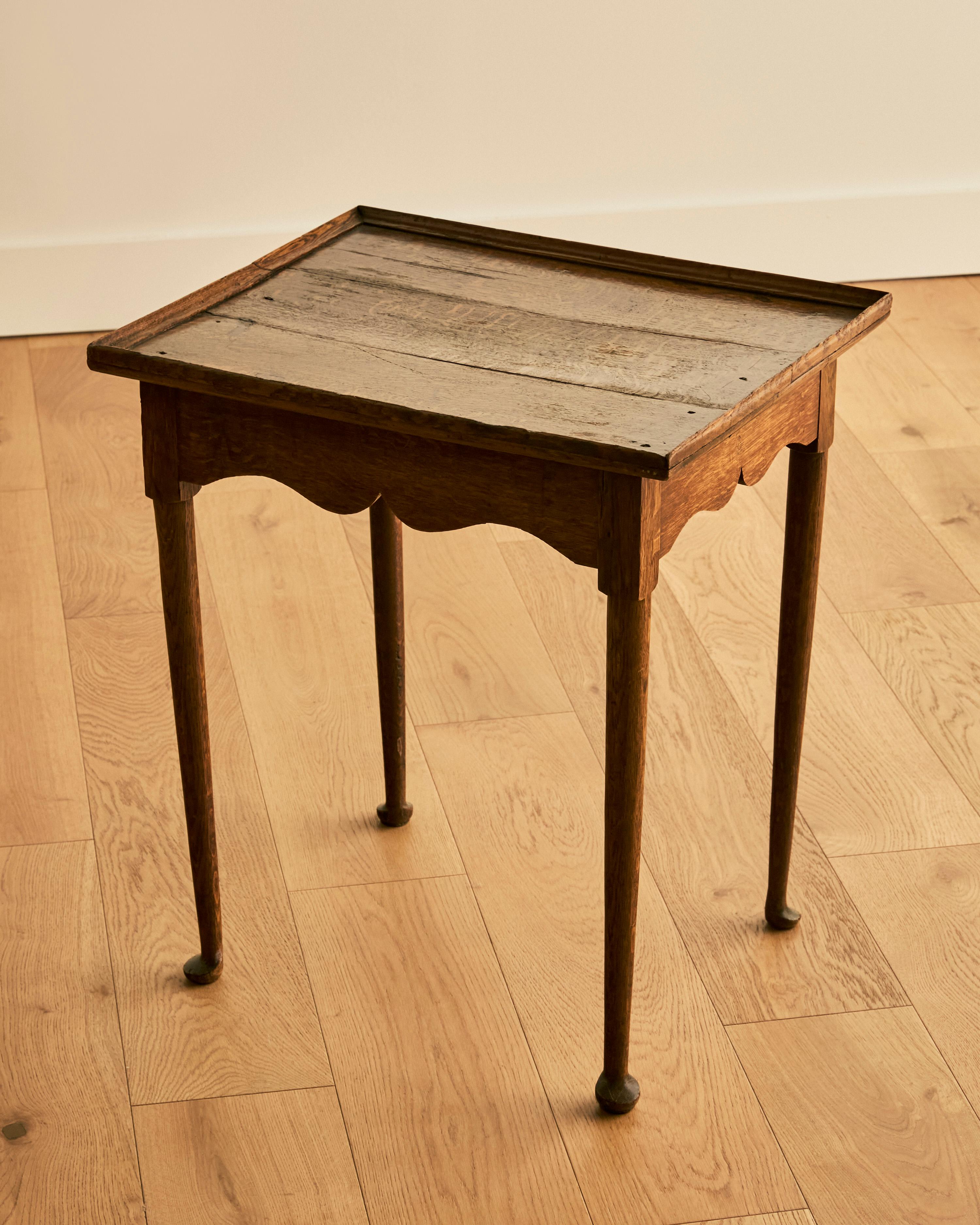 Early oak Queen Anne tea table with scalloped apron, tray, top, and original pad feet. 
