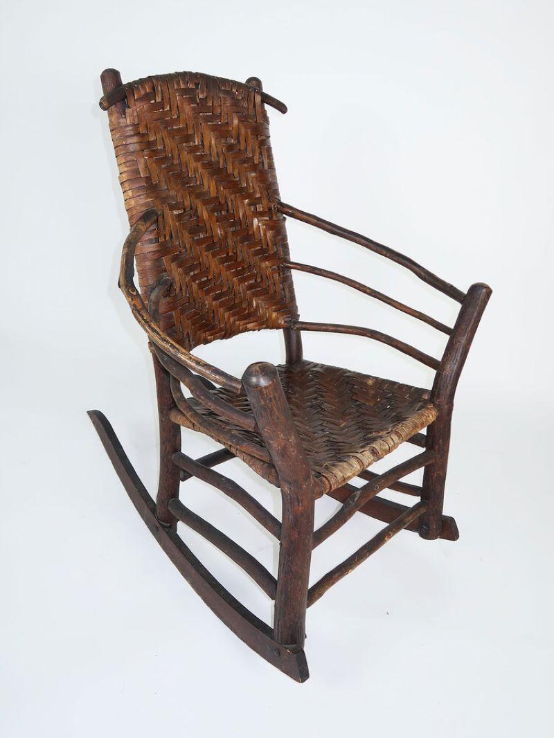 This high-back rocking chair design first appeared in the early Old Hickory Furniture Company catalogs. It has a hickory pole frame with 3-hoop arms, flared front posts and double stretchers. The back and seat are woven of hickory bark in a