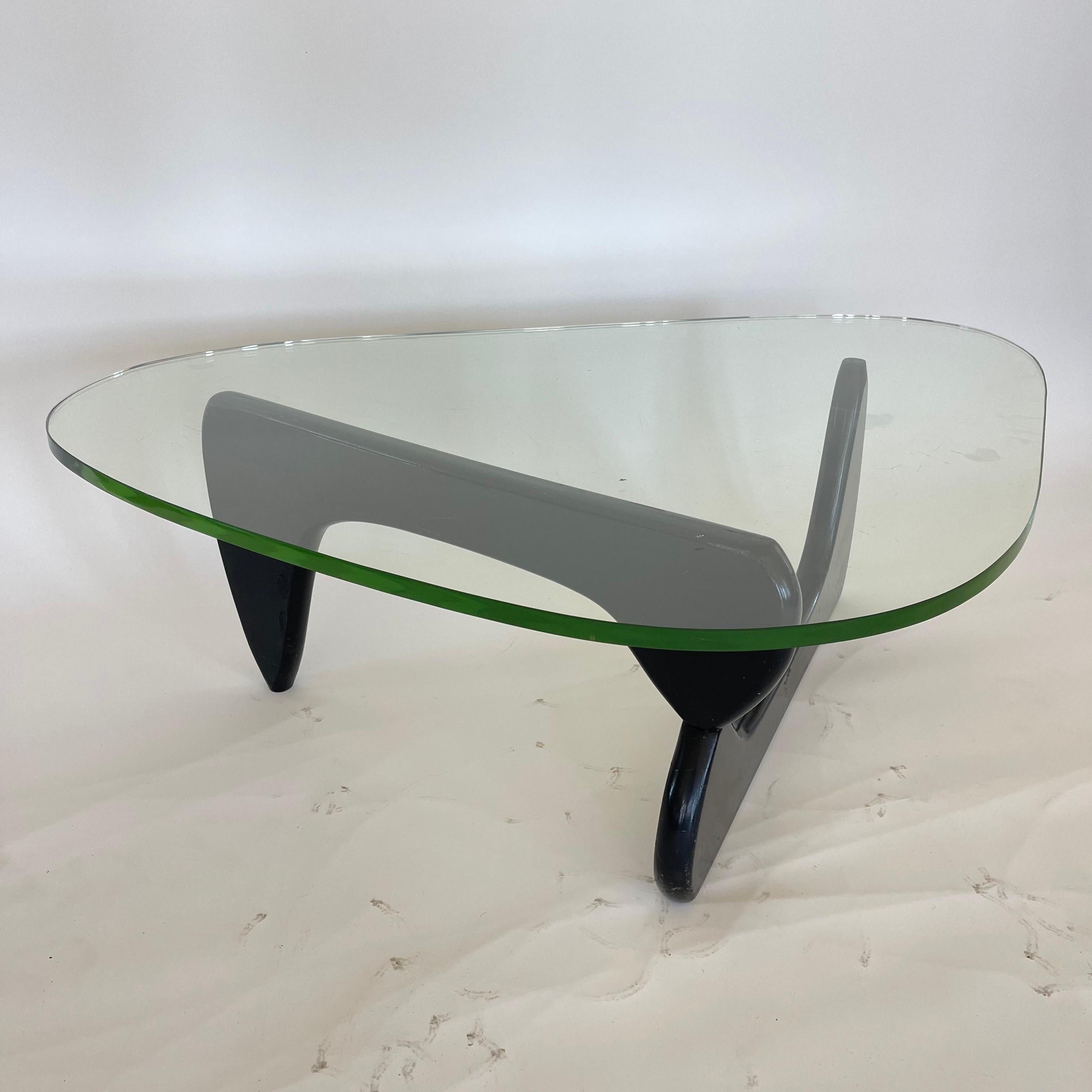 Early IN-50 coffee or cocktail table, rendered in a two part biomorphic form black painted wood frame with an aluminum pin supporting a thick green glass top.
