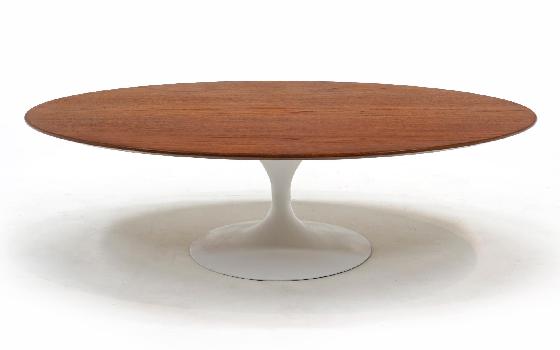 Early, out of production fifty four inch wide oval coffee table with white tulip base designed by Eero Saarinen and produced by Knoll, 1960s.  The table features a walnut top and painted cast iron base.  The early models have the cast iron base