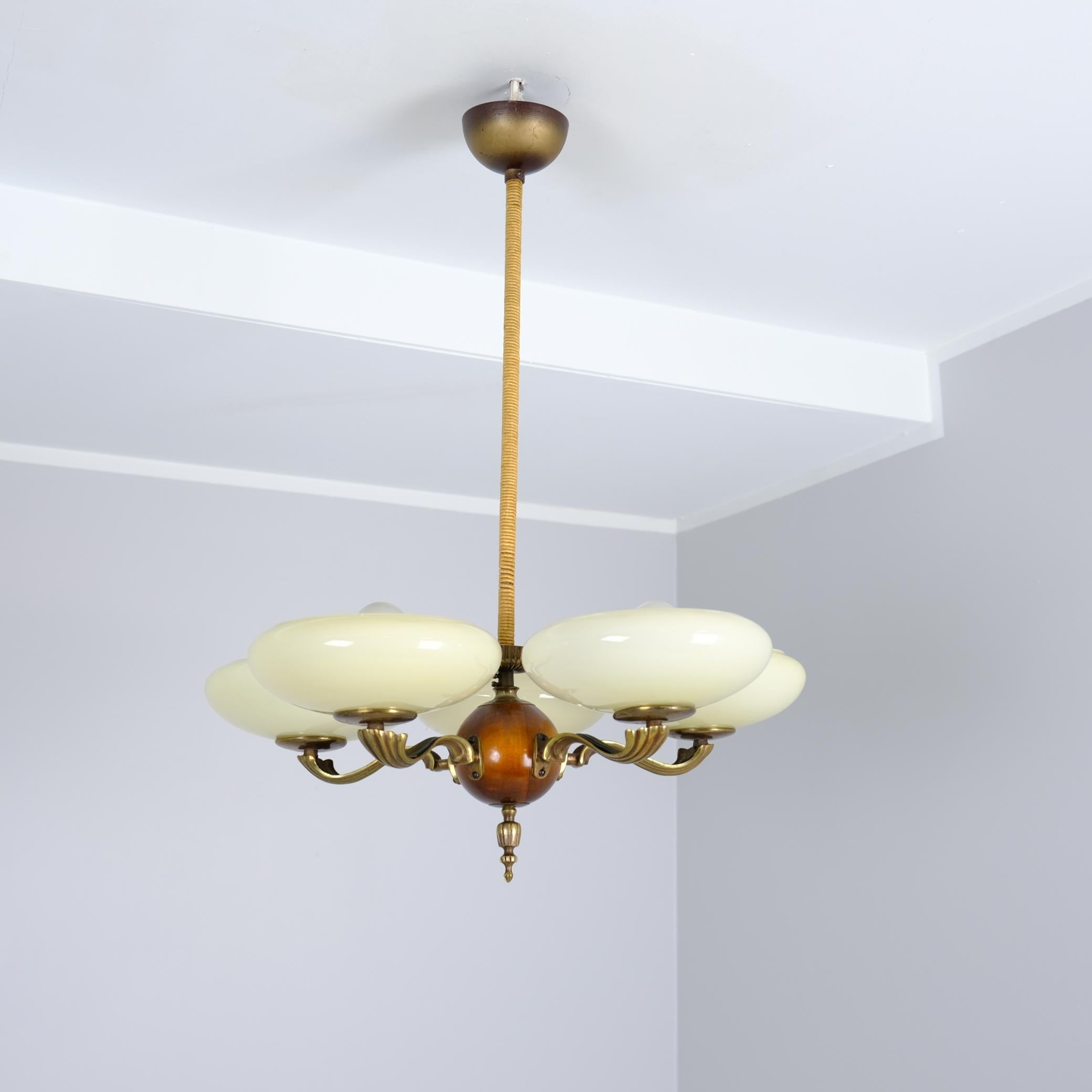 A beautiful early example of Paavo Tynell’s 1930s lighting design, model 1373/5. A decorative piece with a dark stained birch ball in the center, five gracefully curved cast brass arms and blown glass shades. The shades are light beige, delicate and
