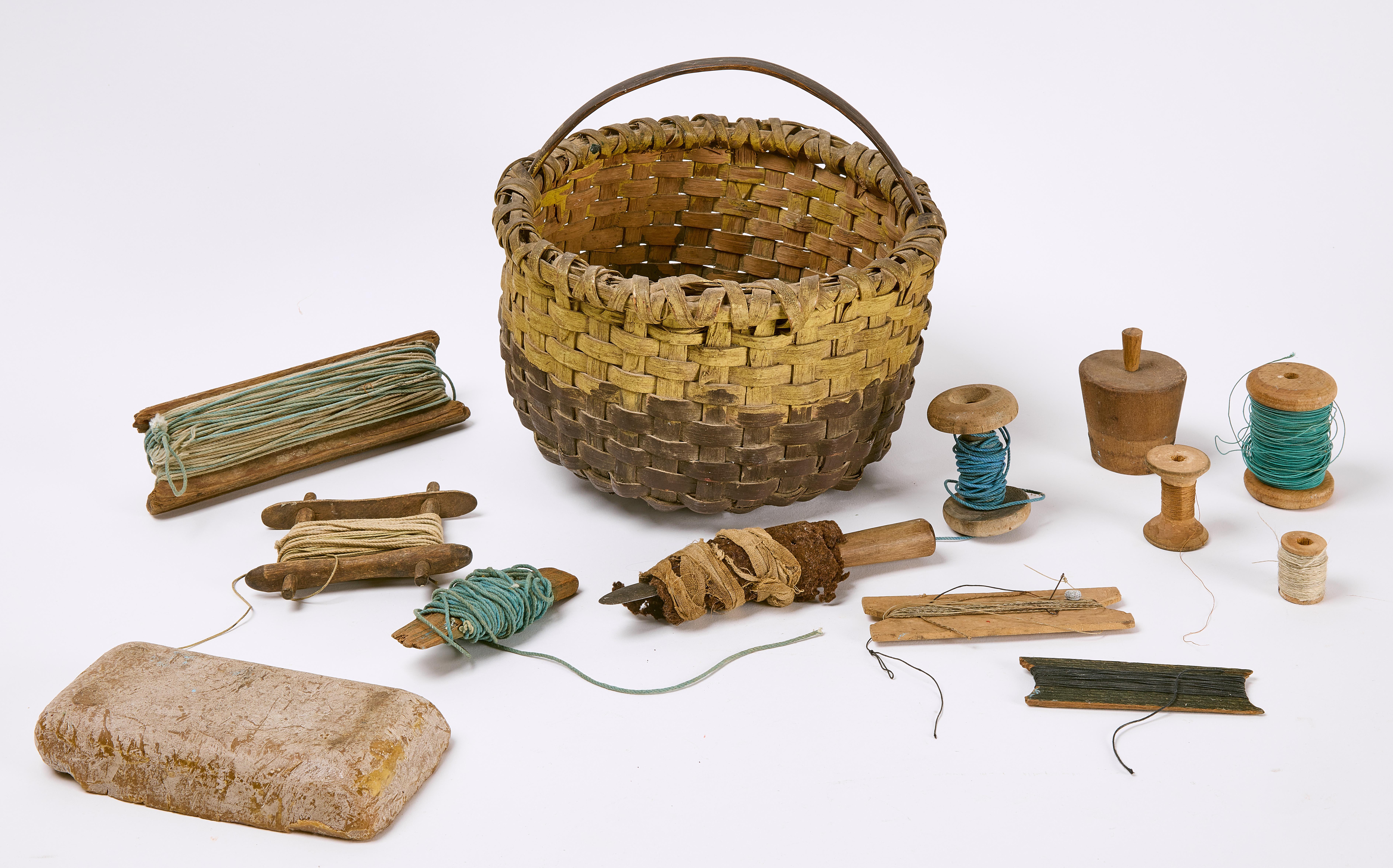 Early 19th century basket with original yellow/white and brown painted basket, including contents of five fishing line spools, six spools of thread, wrapped knife in homemade sheath, three pieces of wooden ware, and one piece of beeswax.

Basket: H