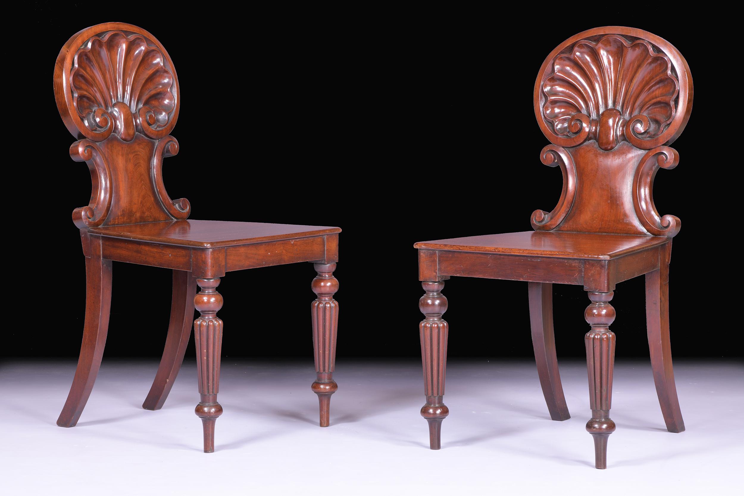 Une belle paire de chaises d'entrée / d'appoint Regency attribuées à Gillows of Lancaster, avec des dossiers en coquille de Saint-Jacques sculptés, des sièges en panneau, le tout reposant sur des pieds en colonne cannelée.

Circa 1820

Anglais.