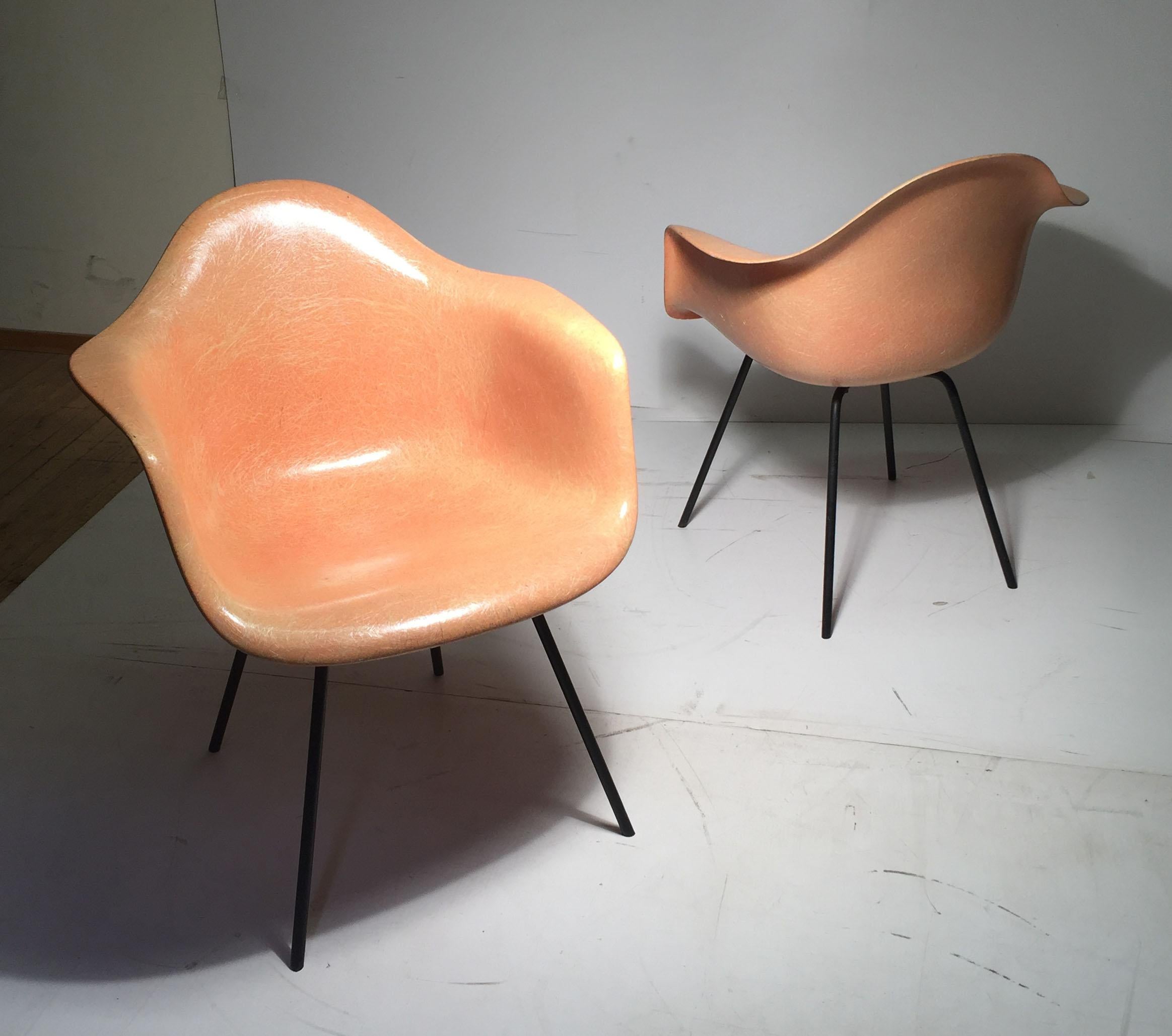 This is a fine early matched pair of possibly Evans or early production years with Herman Miller. They have solid wrought iron X-bases. Large Shock Mounts. Wonderfully faded red fiberglass to a light coral color. Very attractive.