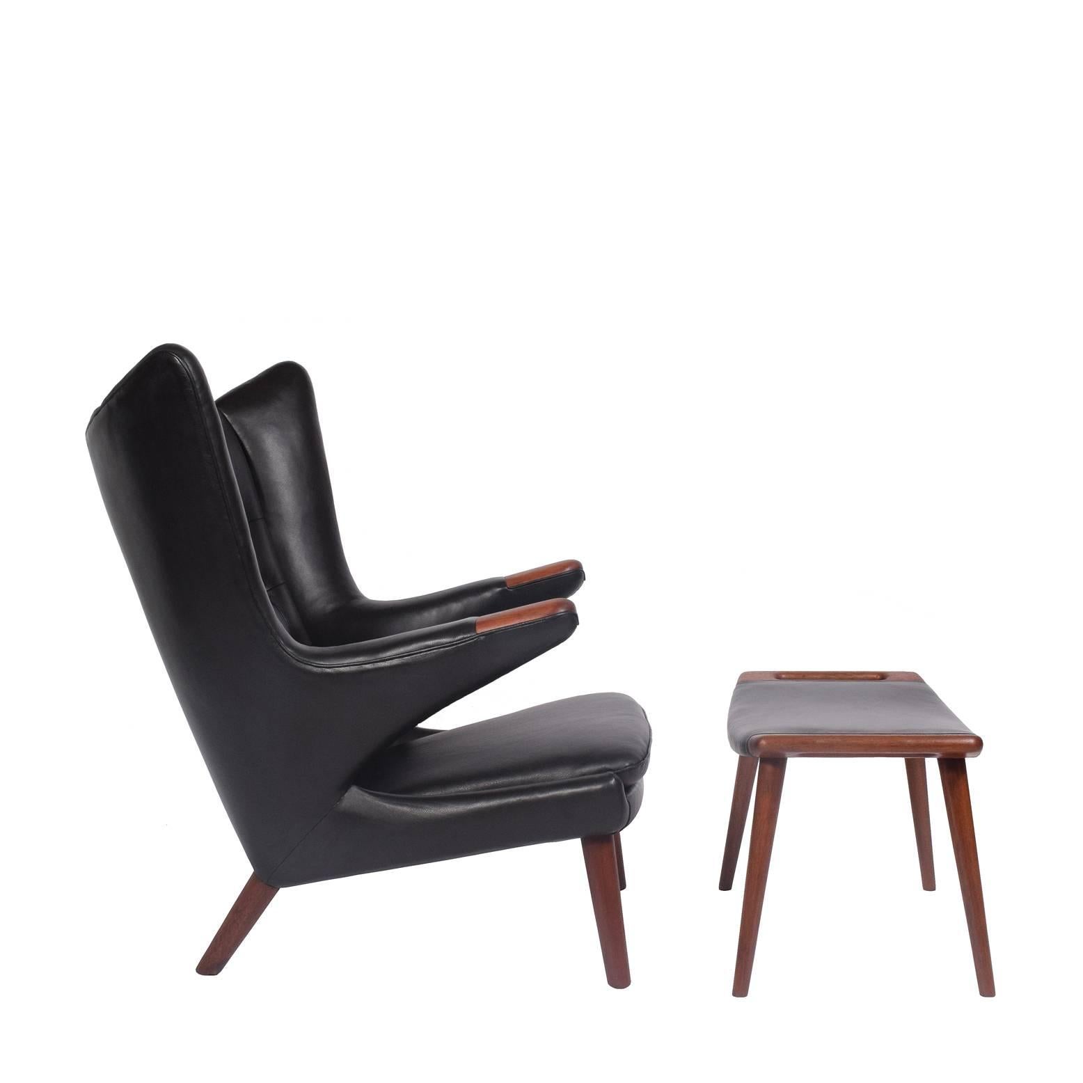 Iconic lounge chair and ottoman by Wegner, with solid teak legs and arm. Ottoman solid teak frame. Reupholstered in black leather.
Early 1950s production. Made by A.P. Stolen.