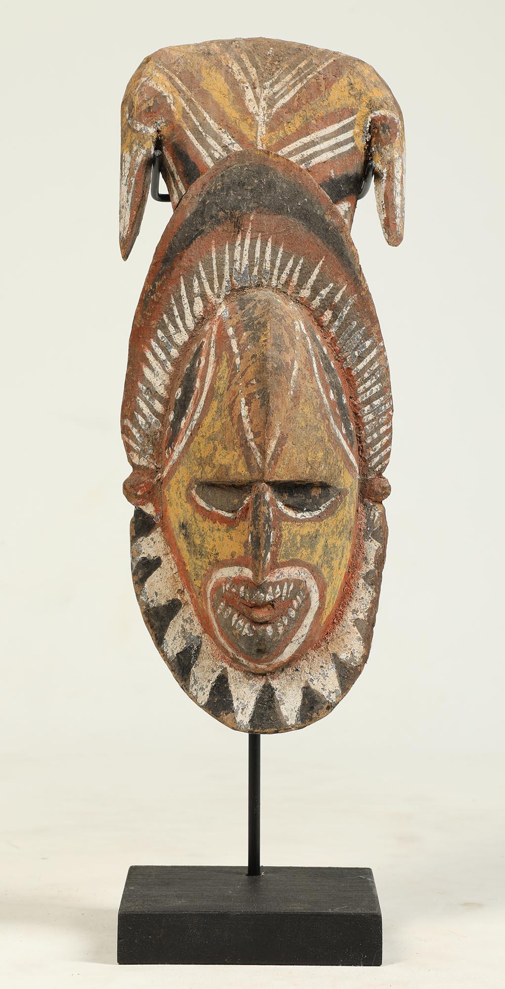 From Papua New Guinea an early painted Maprik carved wood head sculpture or mask, intense expression showing teeth, and two opposing stylized birds on top. Mid 20th century. Faded polychrome pigments with yellow, white, black and red. 
Mask is 10