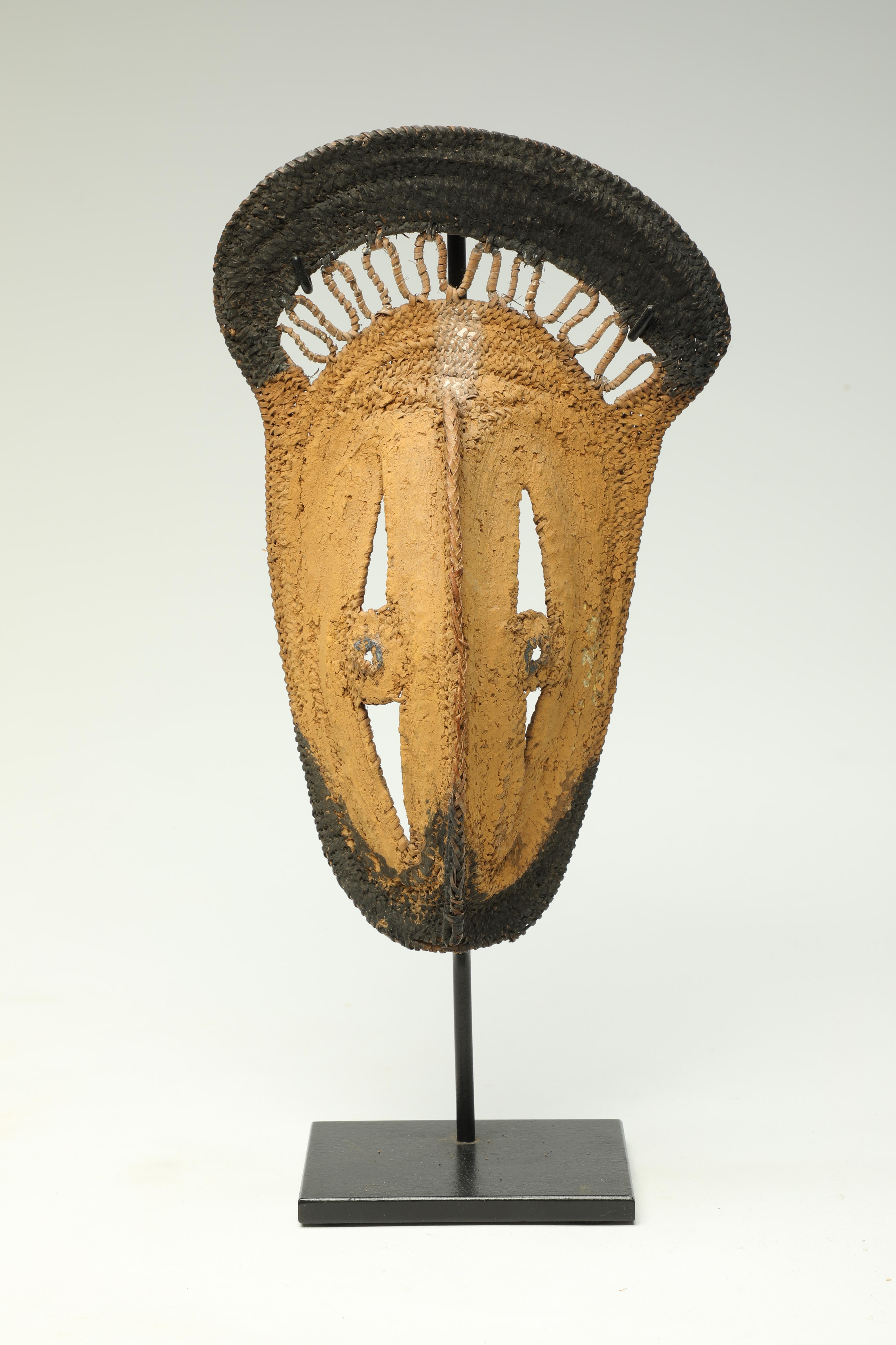 Early Papua New Guinea Sepik River area tightly woven raffia yam mask with areas of heavy yellow and black pigments. In profile small bird beak form at bottom.
Mask is 8 1/2 inches high, on custom metal base total height 11 inches.

