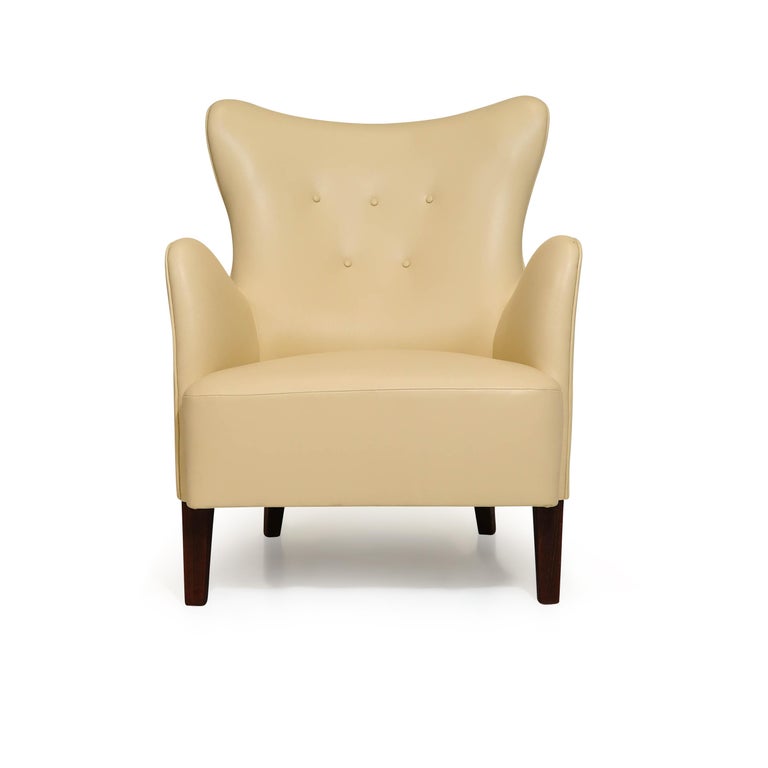 Early Scandinavian lounge chair designed by Perter Hvidt. The chair crafted of a solid wood frame, hand-tied springs, and horsehair padding. The curved button-tufted backrest offers excellent back support. Newly upholstered in a soft yellow cream