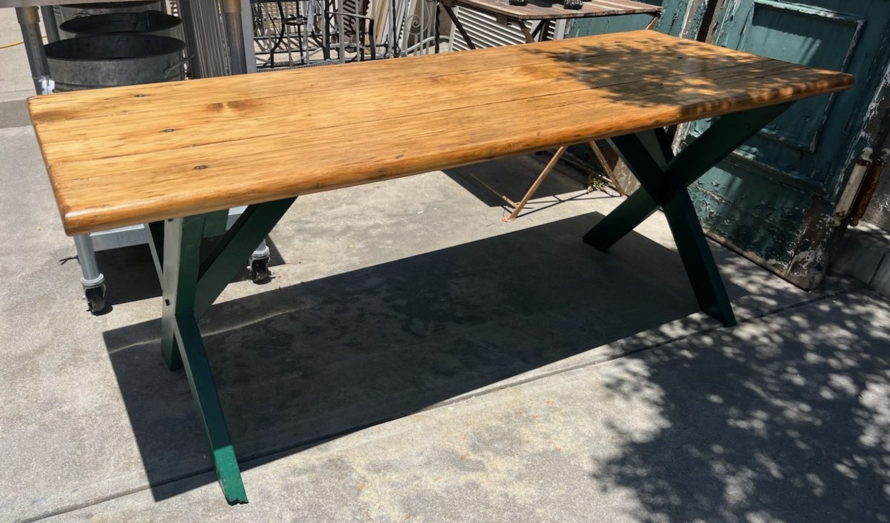 Cette ancienne table de pique-nique d'intérieur/extérieur ou table de sciage a un plateau en planches épaisses et la base est peinte en vert. La planche supérieure est  Il s'agit d'une table très robuste.