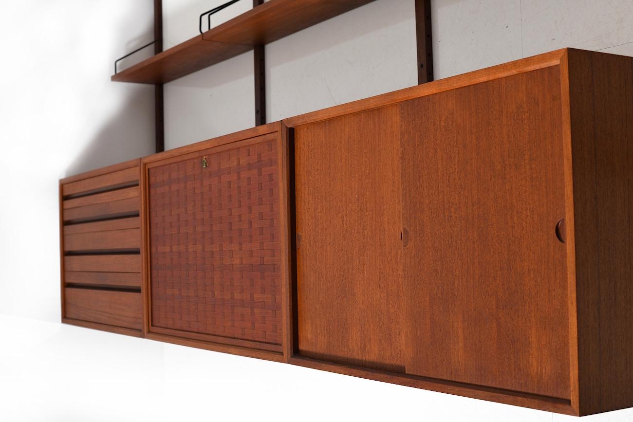 Cado wall system in teak. Royal system. Designed by Poul Cadovius. Manufactured by Cado. Five shelves, four cabinets, four wall brackets. Very good vintage condition. Ready to hang. Nice teak color.
Size: 38.5 x 244.5 x 198.0 (wall brackets) CM (D