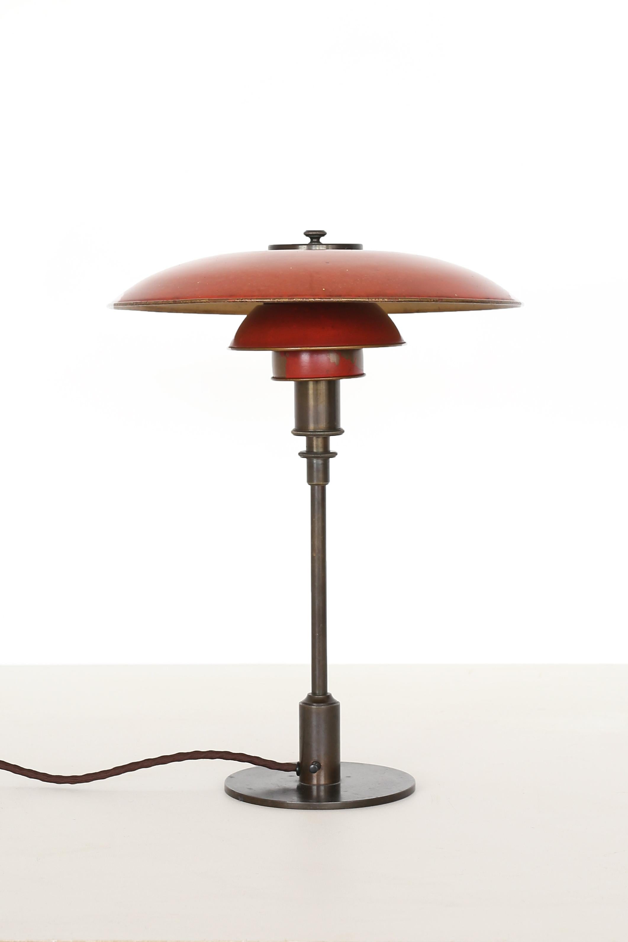 Seltene frühe 'PH 3/2 Tischlampe' mit patiniertem, gebräuntem Messinggestell und originalen rot/goldenen Kupferschirmen. Entworfen 1926 und hergestellt bei Louis Poulsen, 1927-1928. Gestempelt 'PAT.APPL.' P.O.A.

Die Lampe befindet sich in einem