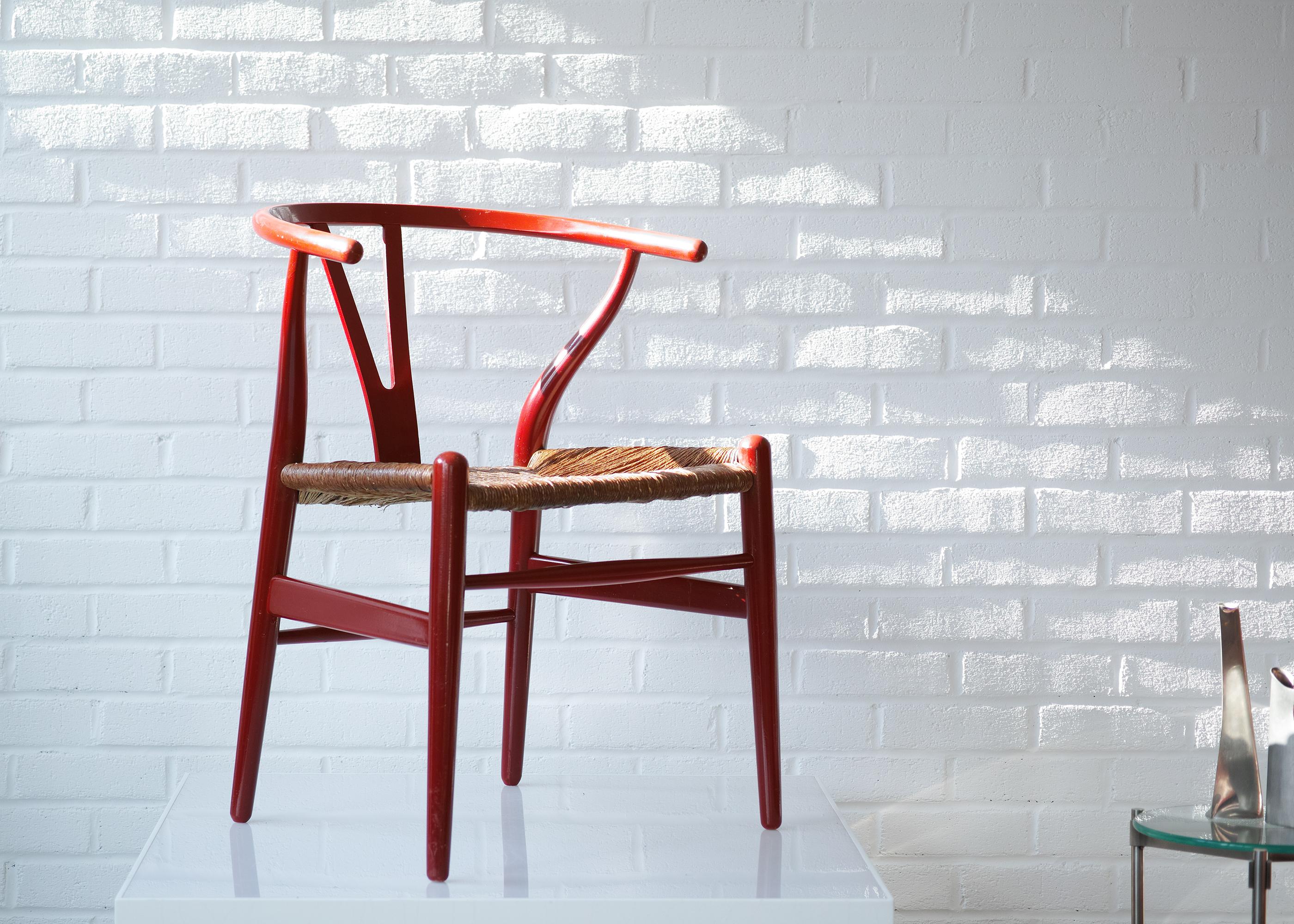 Wir bieten Ihnen dieses frühe Exemplar von Hans Wegners ikonischem CH24 Wishbone Stuhl, hergestellt von Carl Hansen & Son. Er ist rot lackiert und hat einen geflochtenen Sitz aus Papierkordel. Auf der Unterseite des Sitzes ist die Marke 